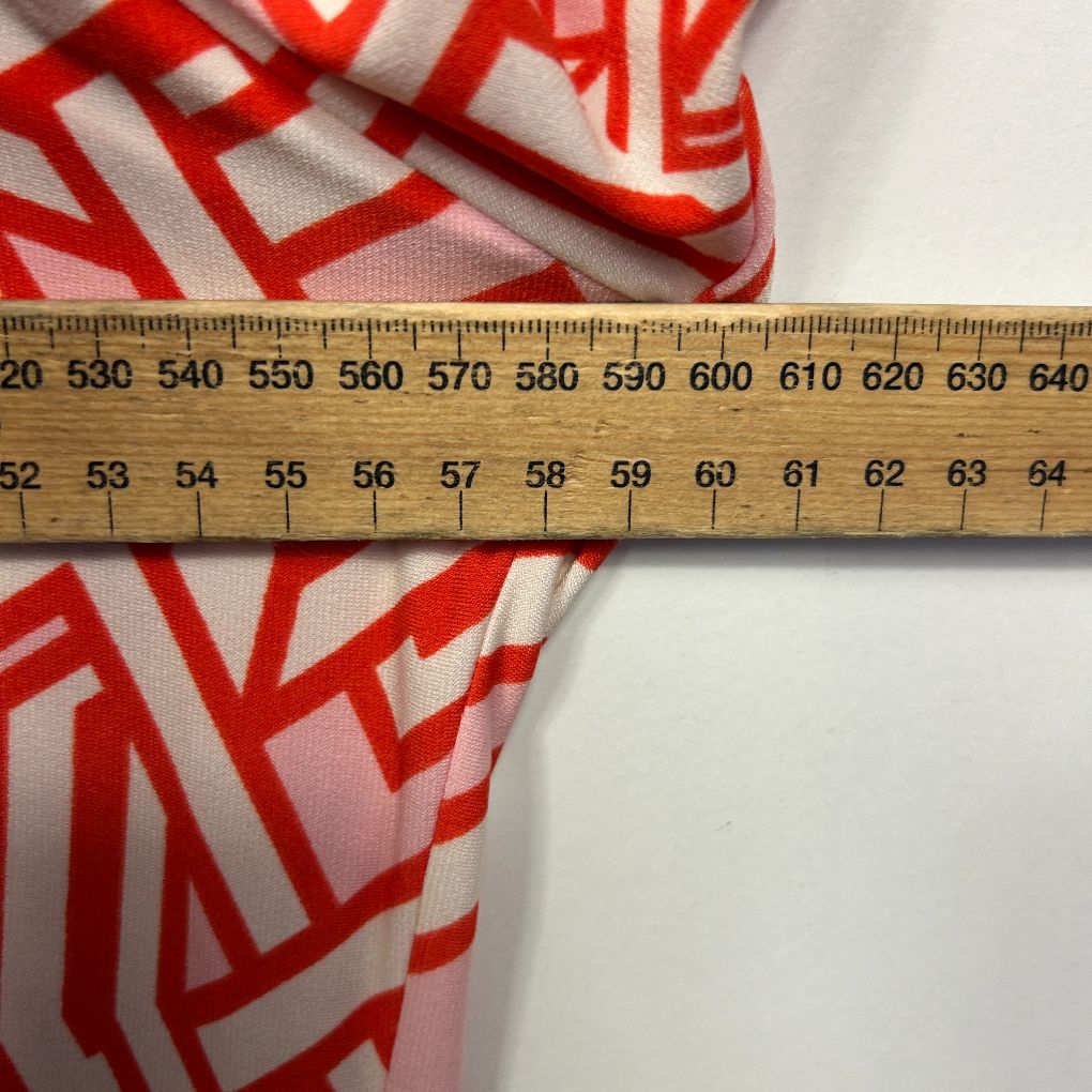 Red and white geometric patterned fabric detail view with measuring tape