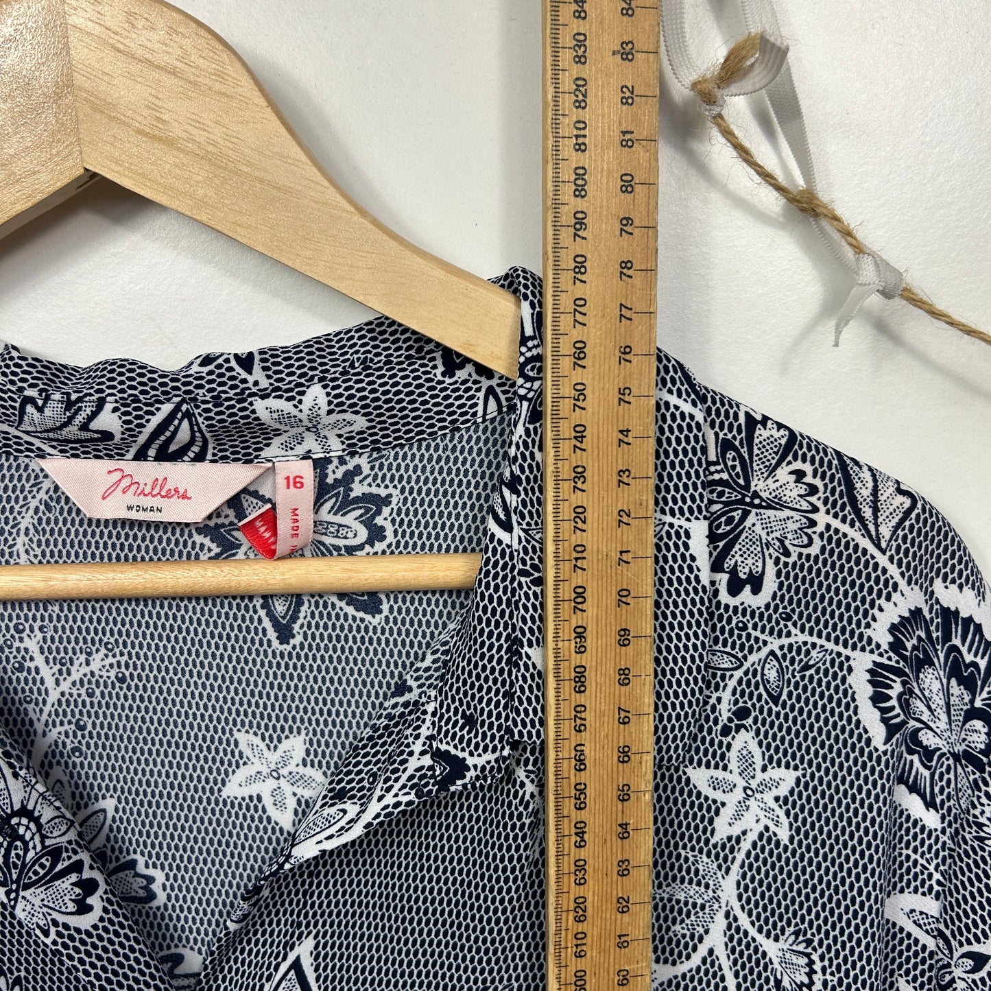 Black and white floral print top detail view on hanger with measuring ruler