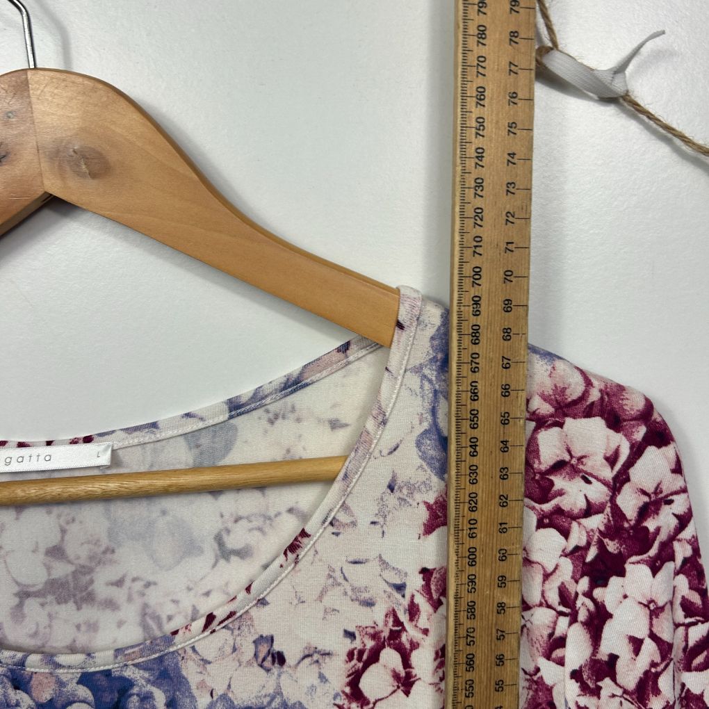 Floral print top detail view on wooden hanger with measuring tape
