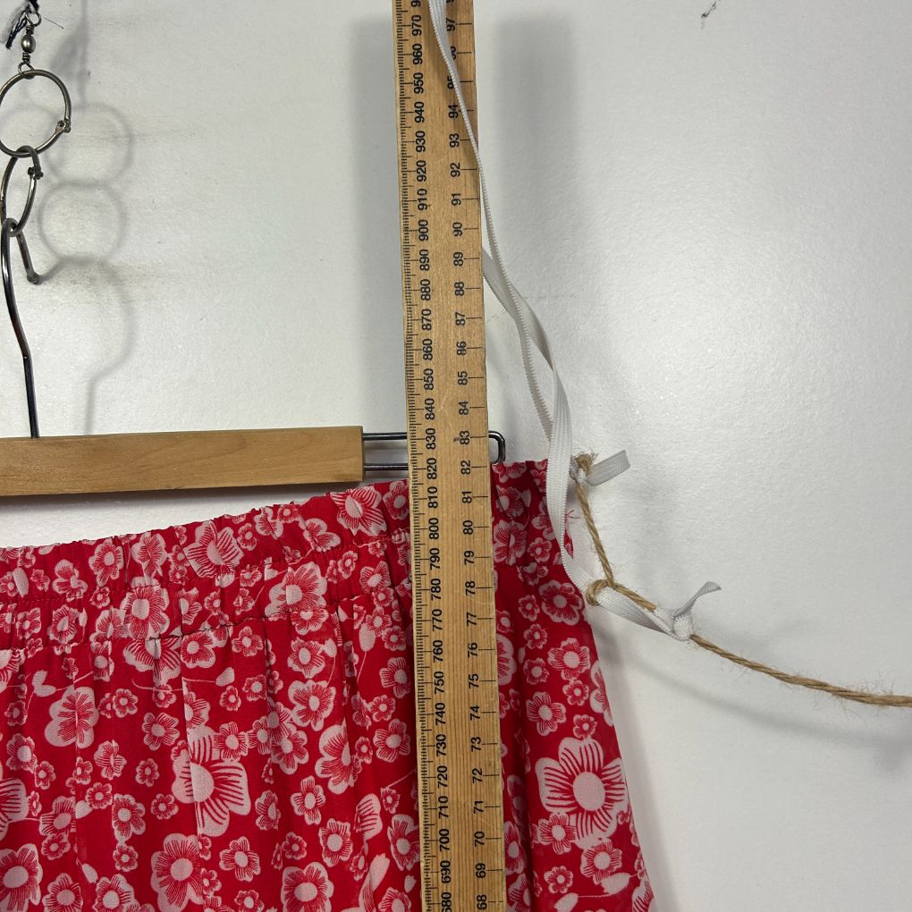Red floral fabric detail view with measuring tape