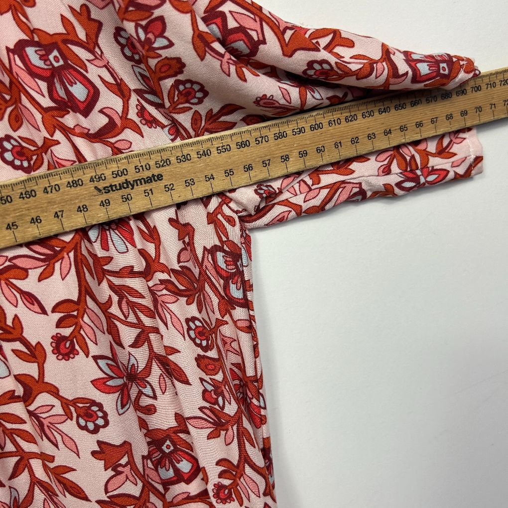 Red and cream floral fabric with measuring tape detail view