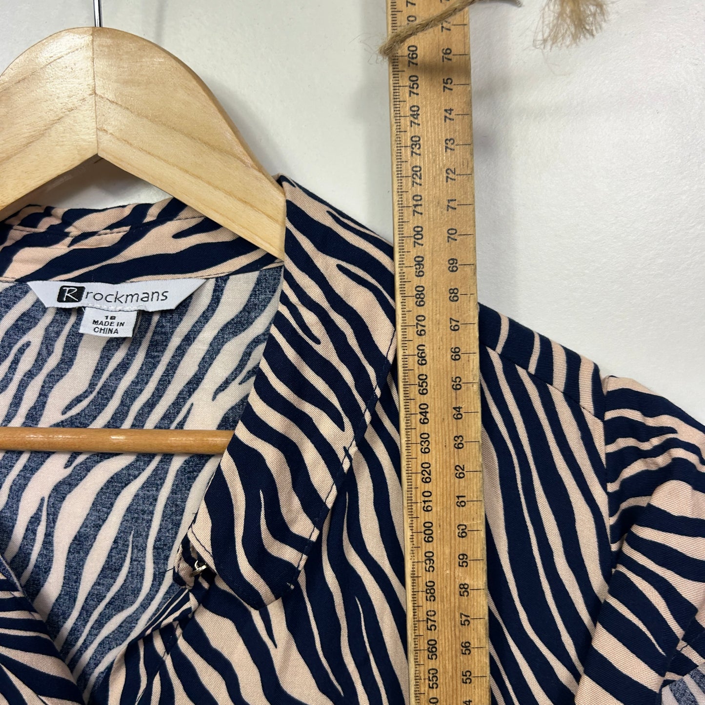 Navy and white striped shirt detail view with wooden hanger