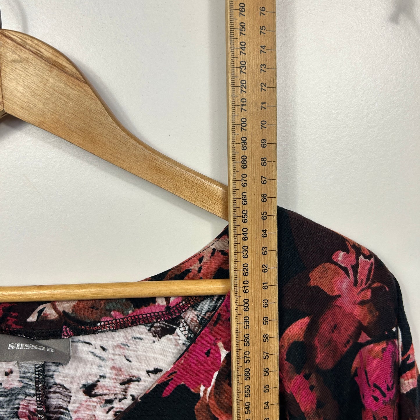 Black floral top detail view with wooden hanger