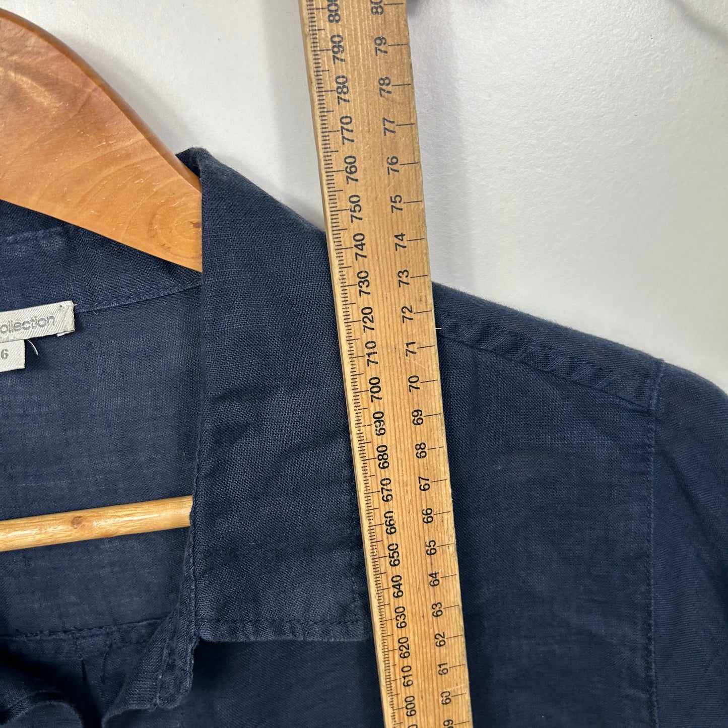 Navy shirt front view with wooden collar detail and measuring tape