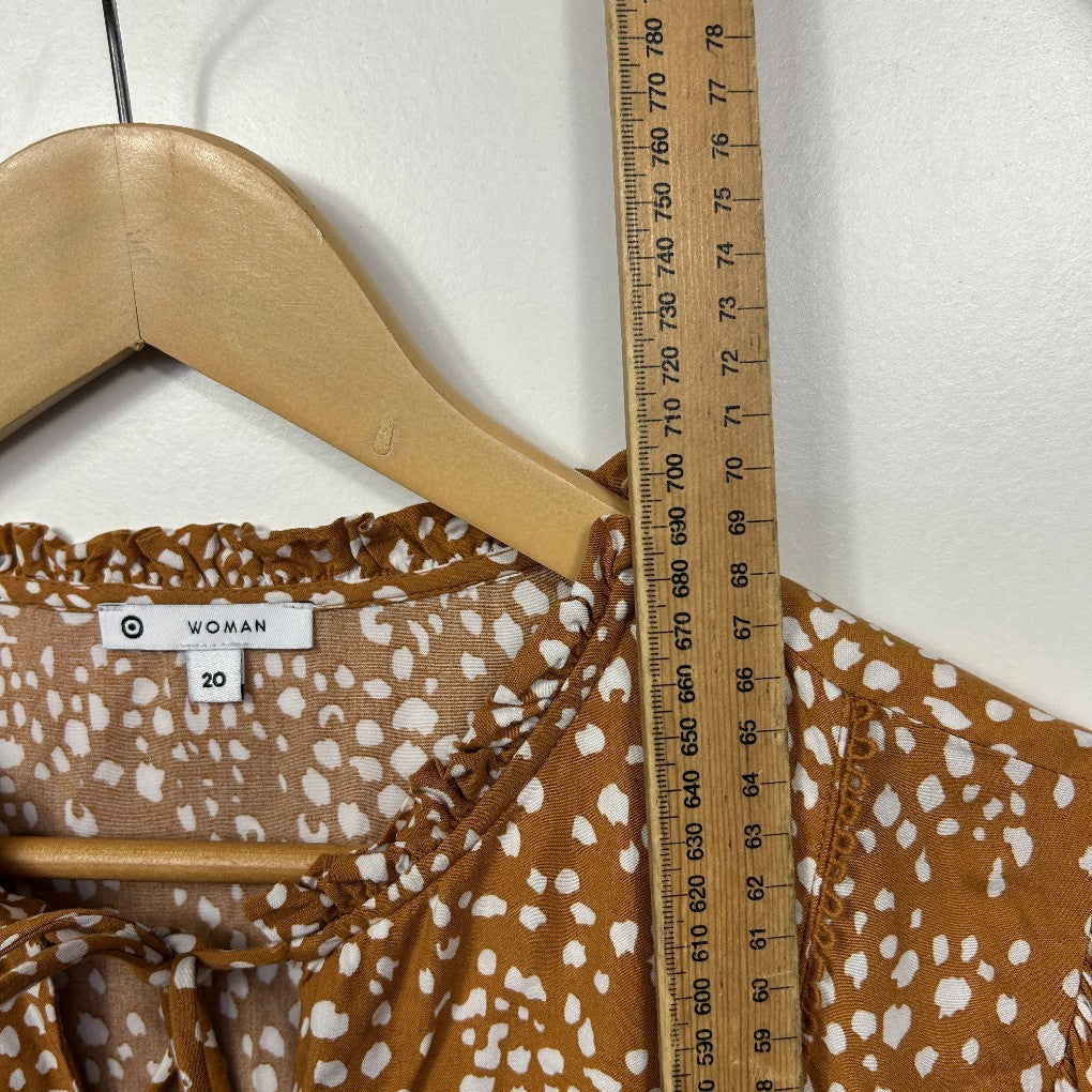 Brown and white spotted dress front view on hanger with ruler