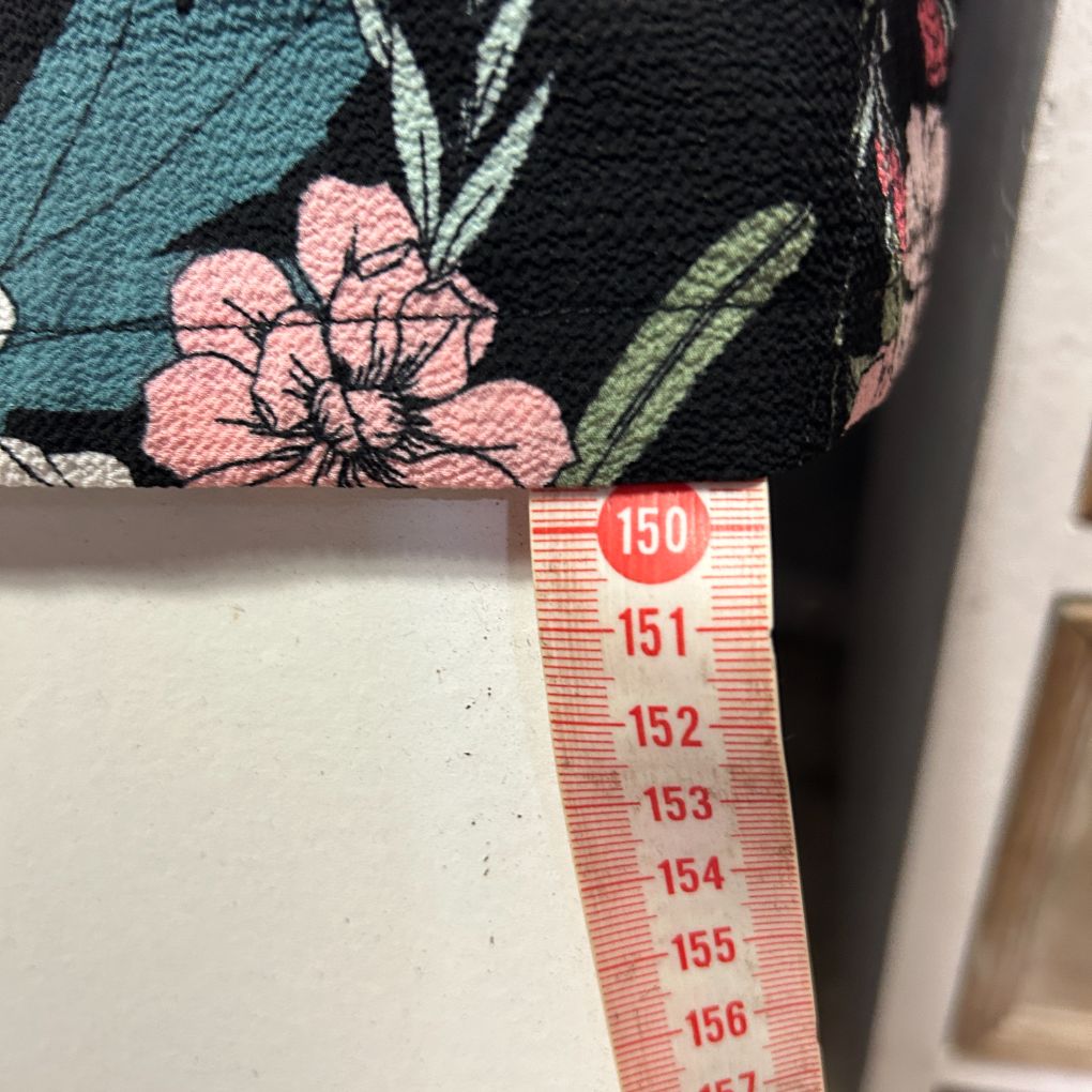 Floral embroidered fabric detail view with measuring tape