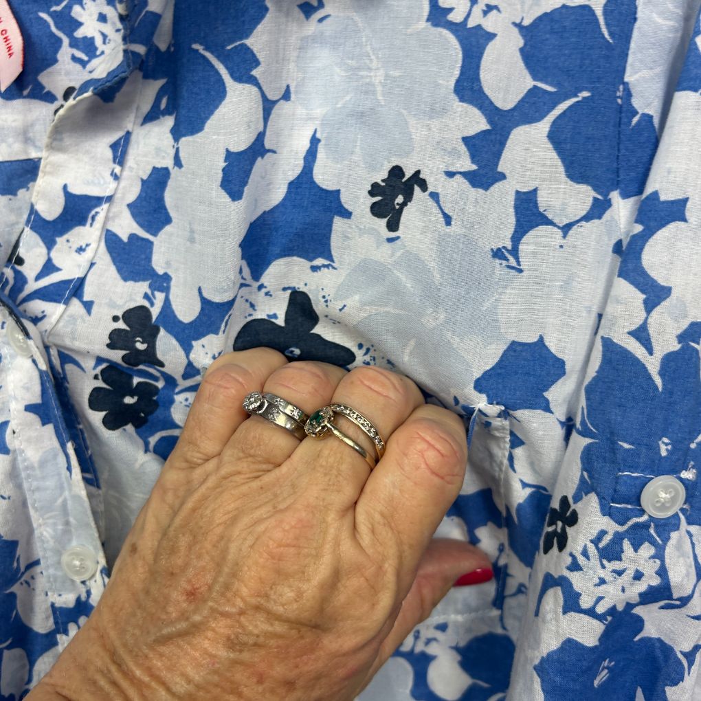 Blue and white floral shirt detail view with rings on hand