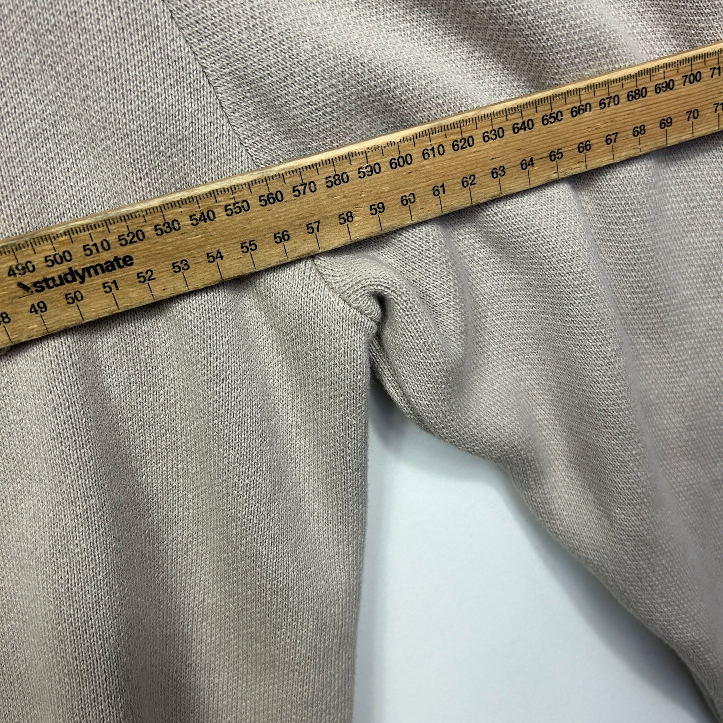 Beige knit fabric detail view with measuring tape