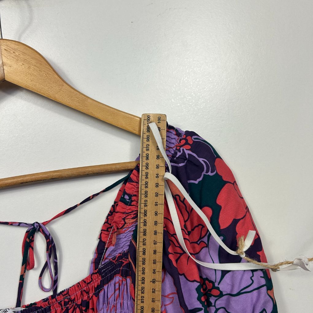 Colorful patterned bikini top detail view with wooden hanger and measuring tape