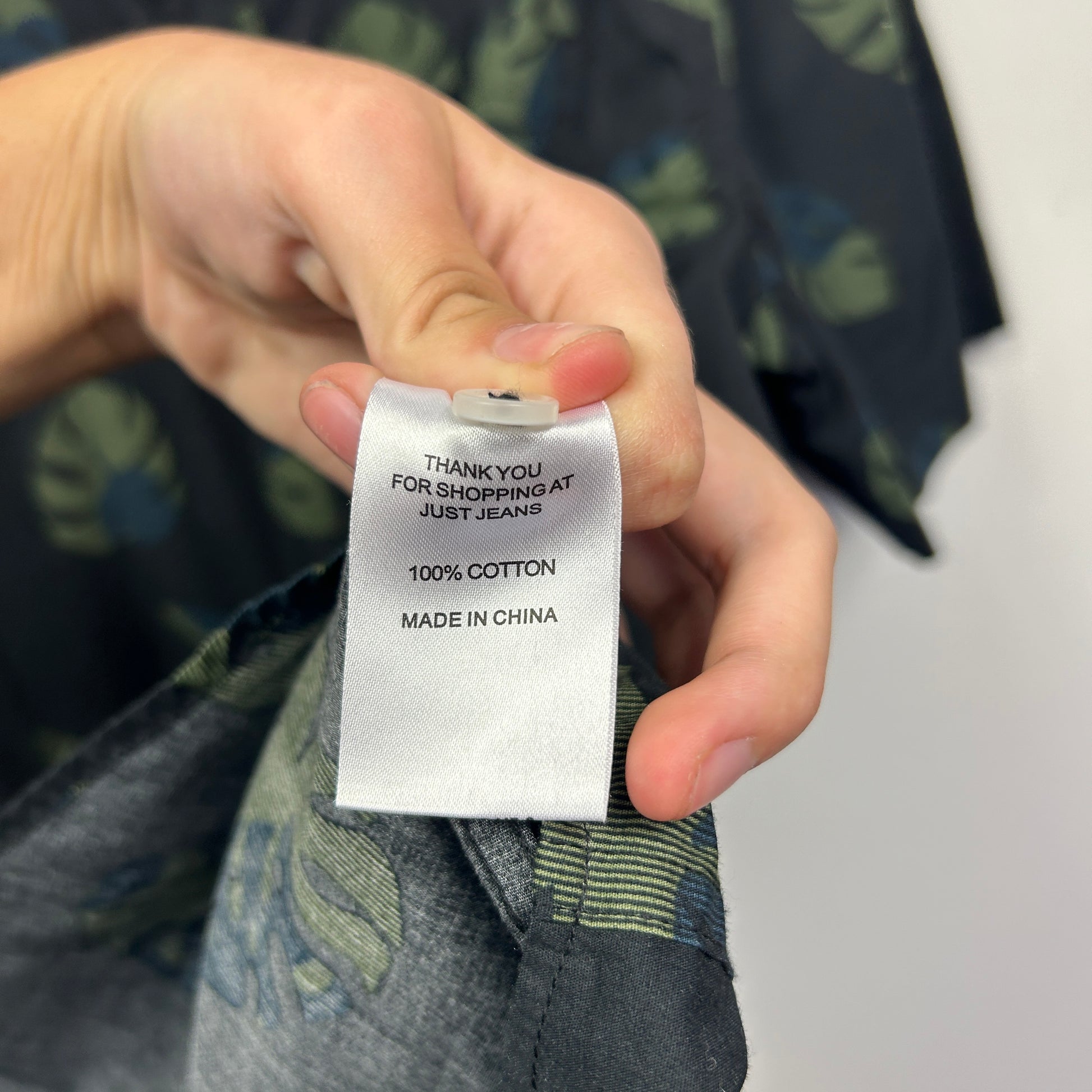 White clothing label detail view showing care instructions and fabric content