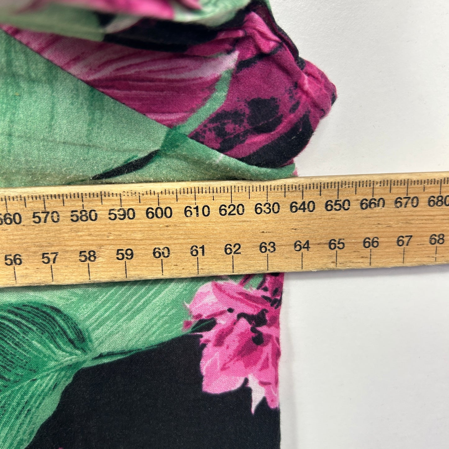 Pink floral fabric with green leaves detail view with measuring ruler