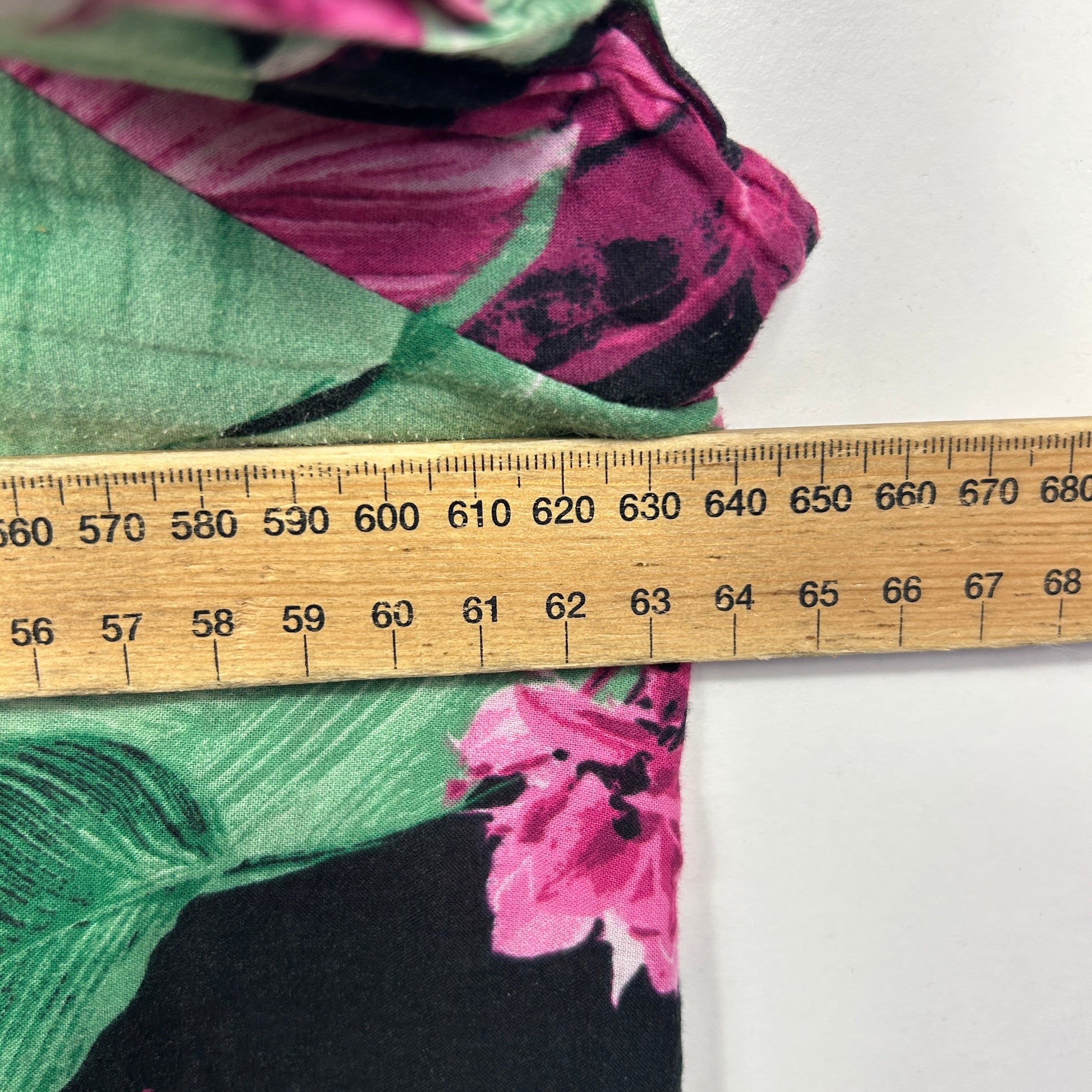 Pink floral fabric with green leaves detail view with measuring ruler