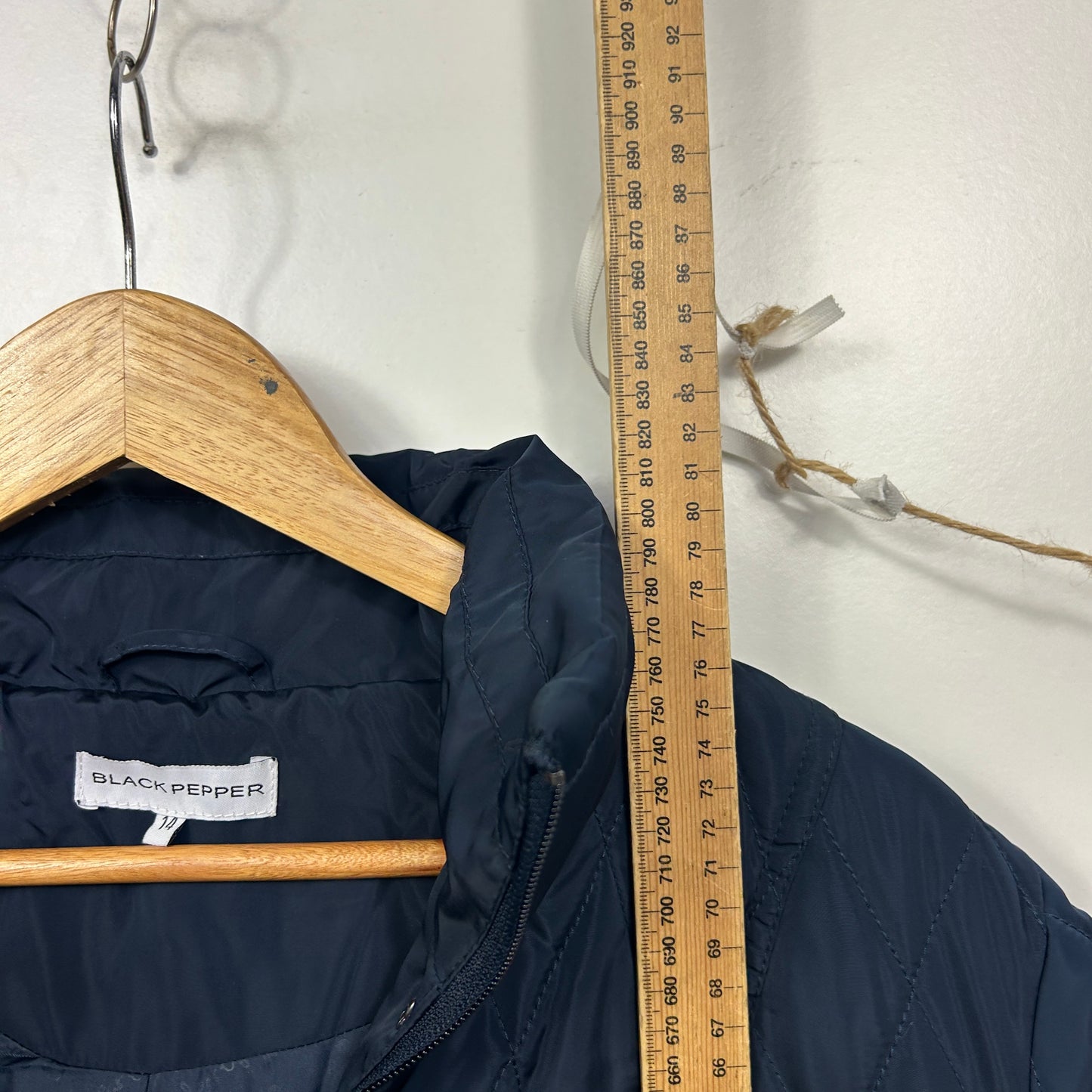 Black jacket front view on wooden hanger with measuring tape