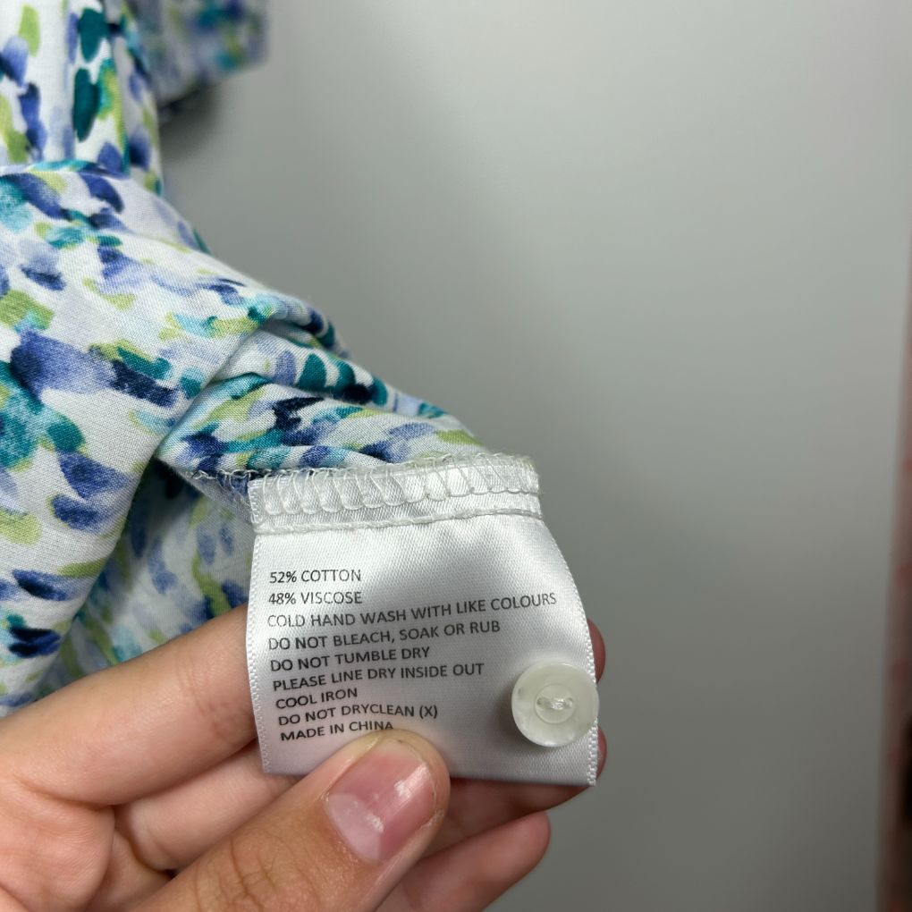 Blue floral top detail view showing care label