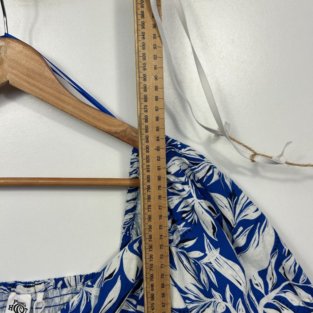 Blue and white floral dress detail view with measuring tape