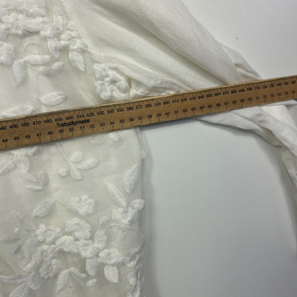 White lace dress detail view with measuring tape