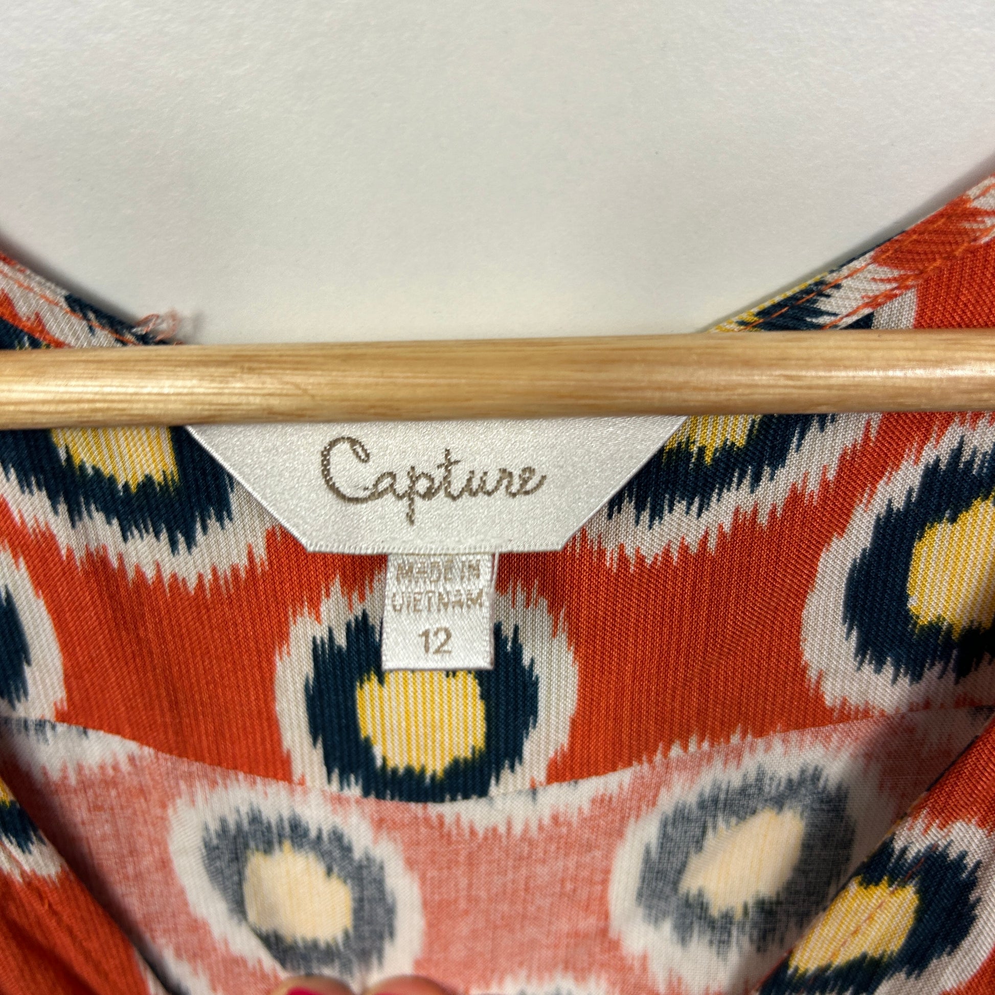 Red and navy geometric patterned knit detail view with wooden hanger