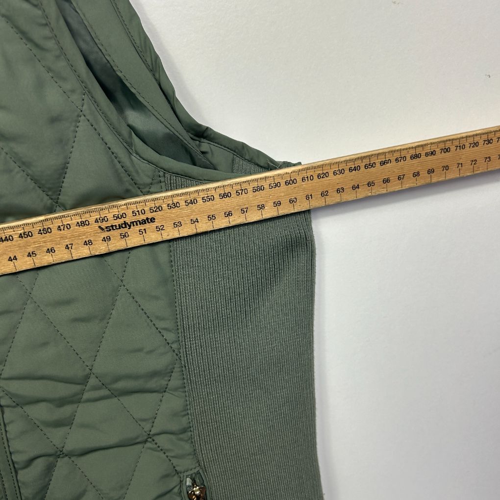 Green quilted vest detail view with measuring tape