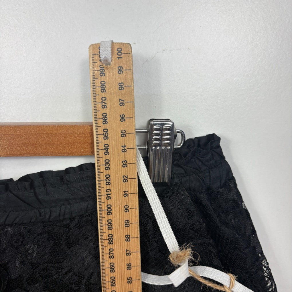 Black textured fabric being measured with wooden ruler detail view