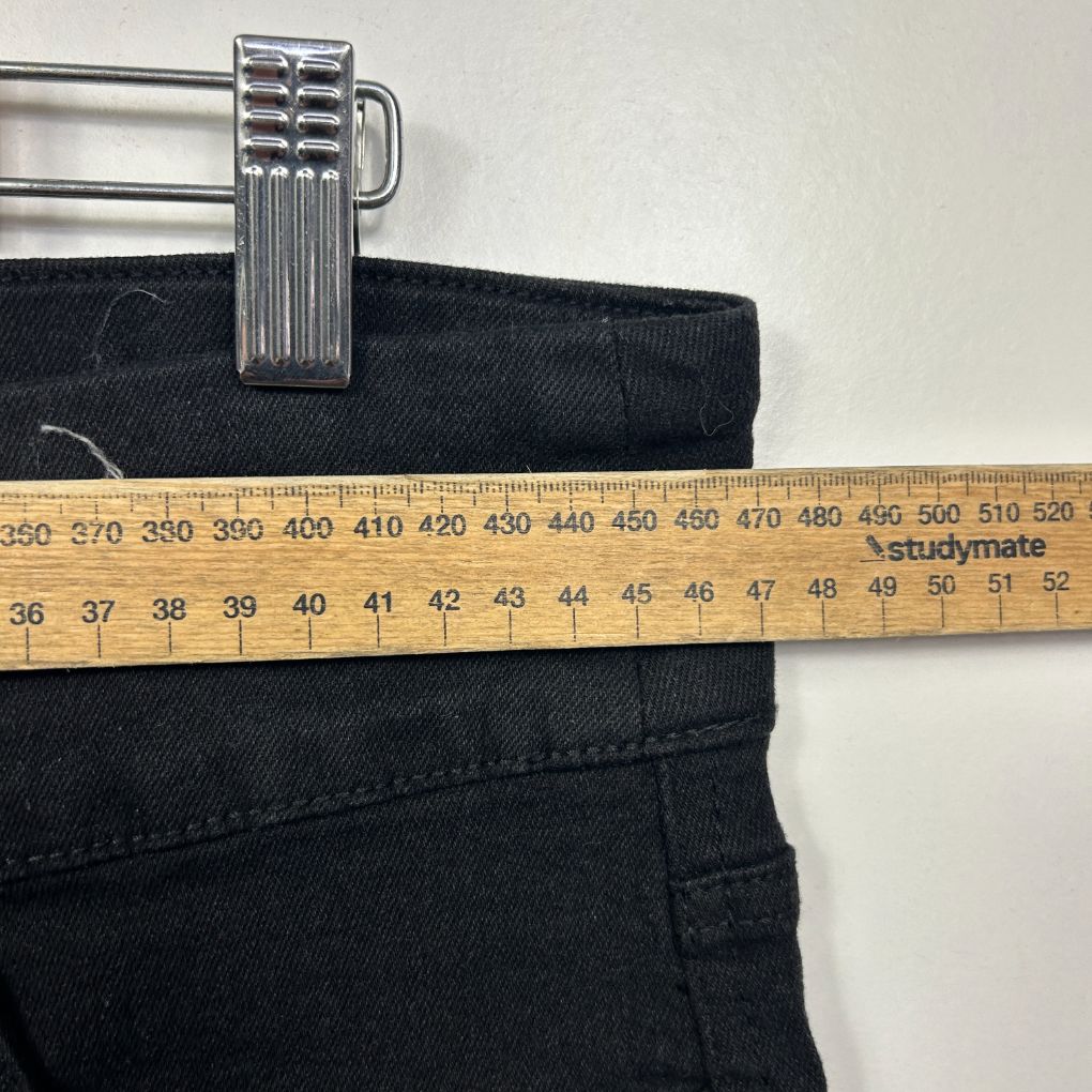 Black jeans waistband detail view with measuring tape