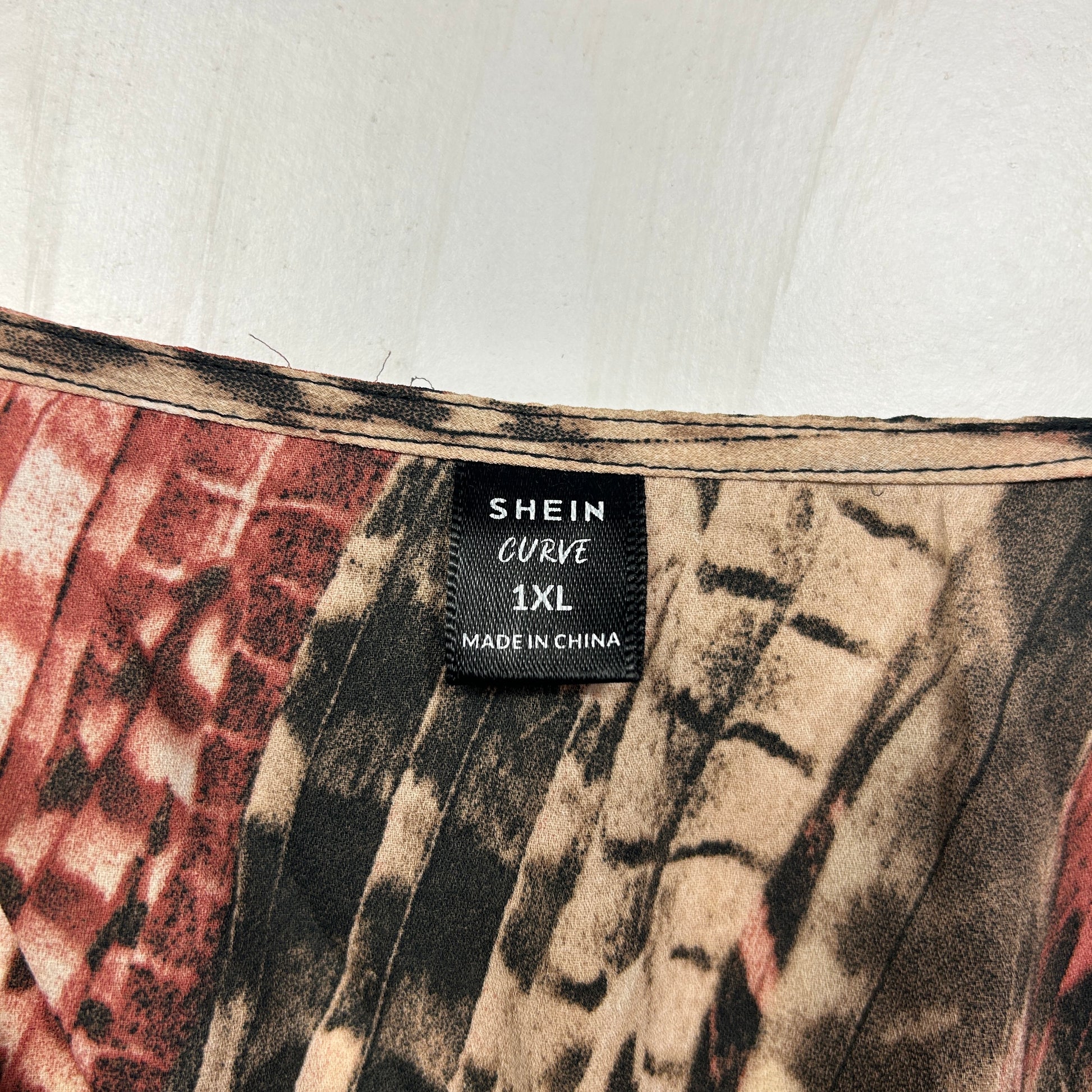 Shein Curve label detail view on beige and red patterned garment