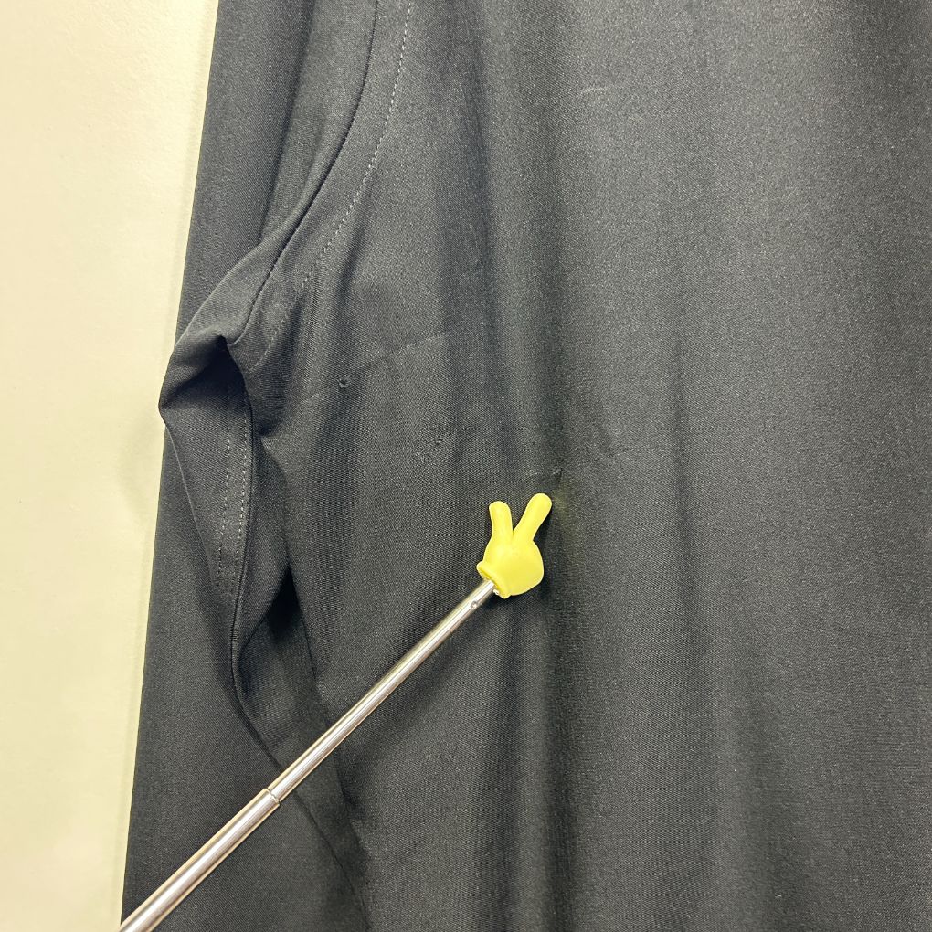 Grey shirt detail view showing yellow button on metal rod