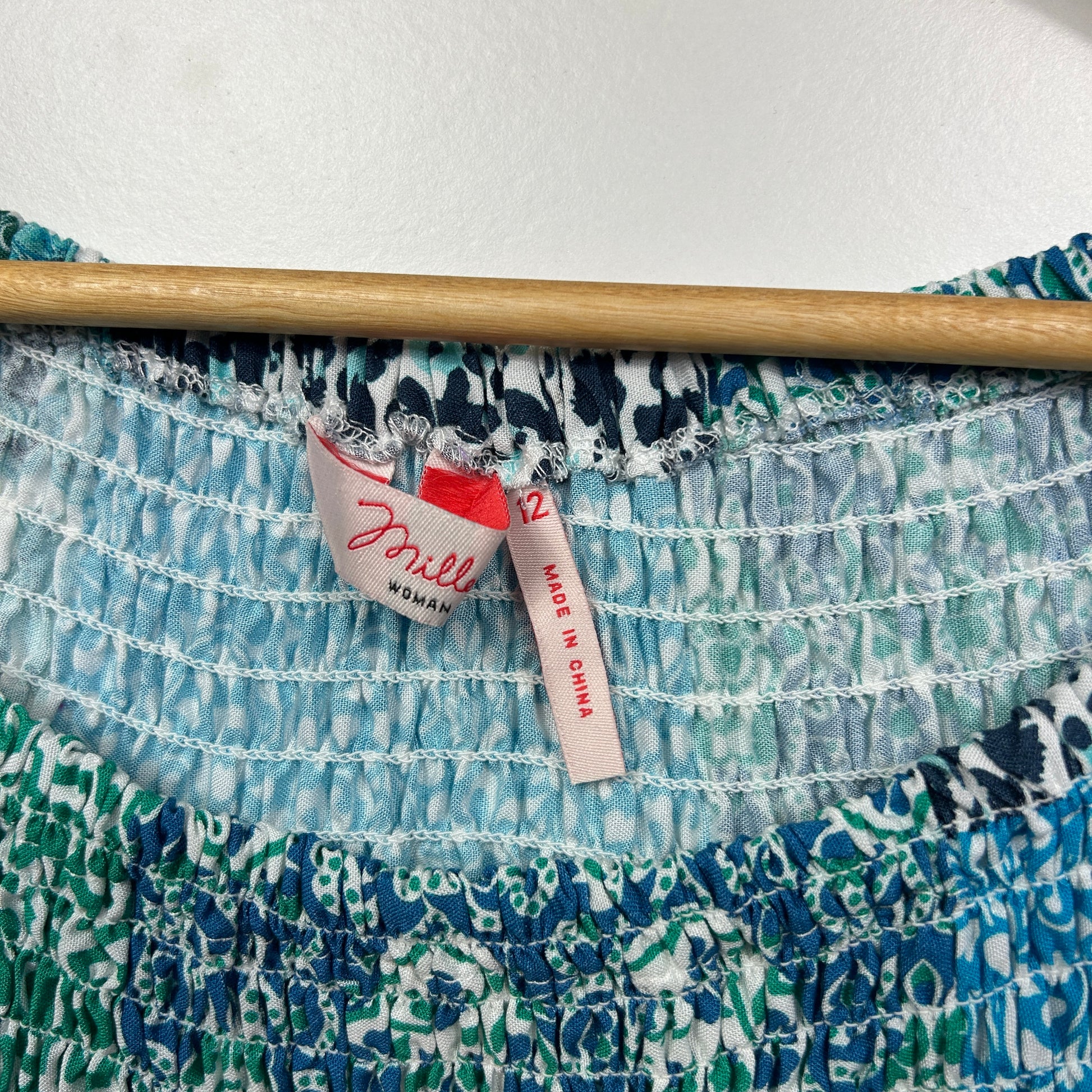 Blue and green patterned top detail view with wooden hanger and label