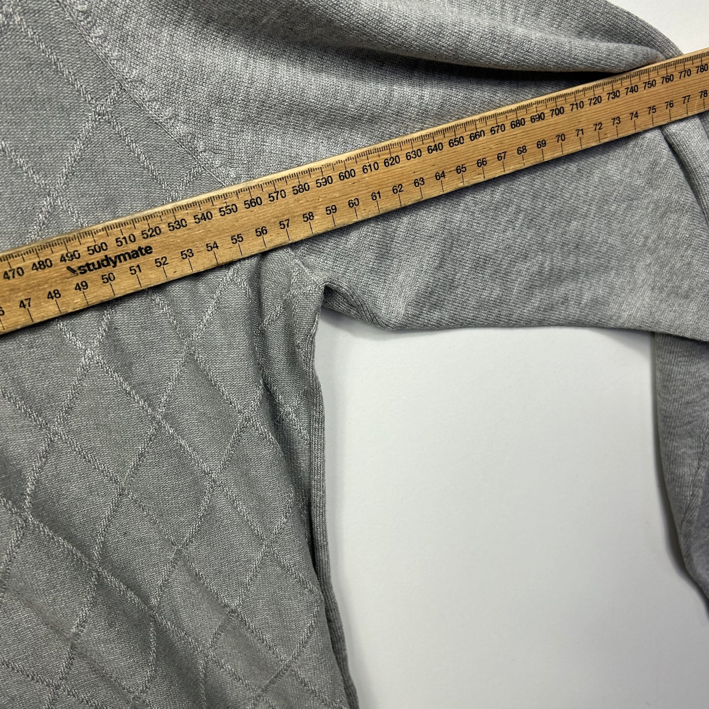 Grey quilted fabric detail view with measuring tape