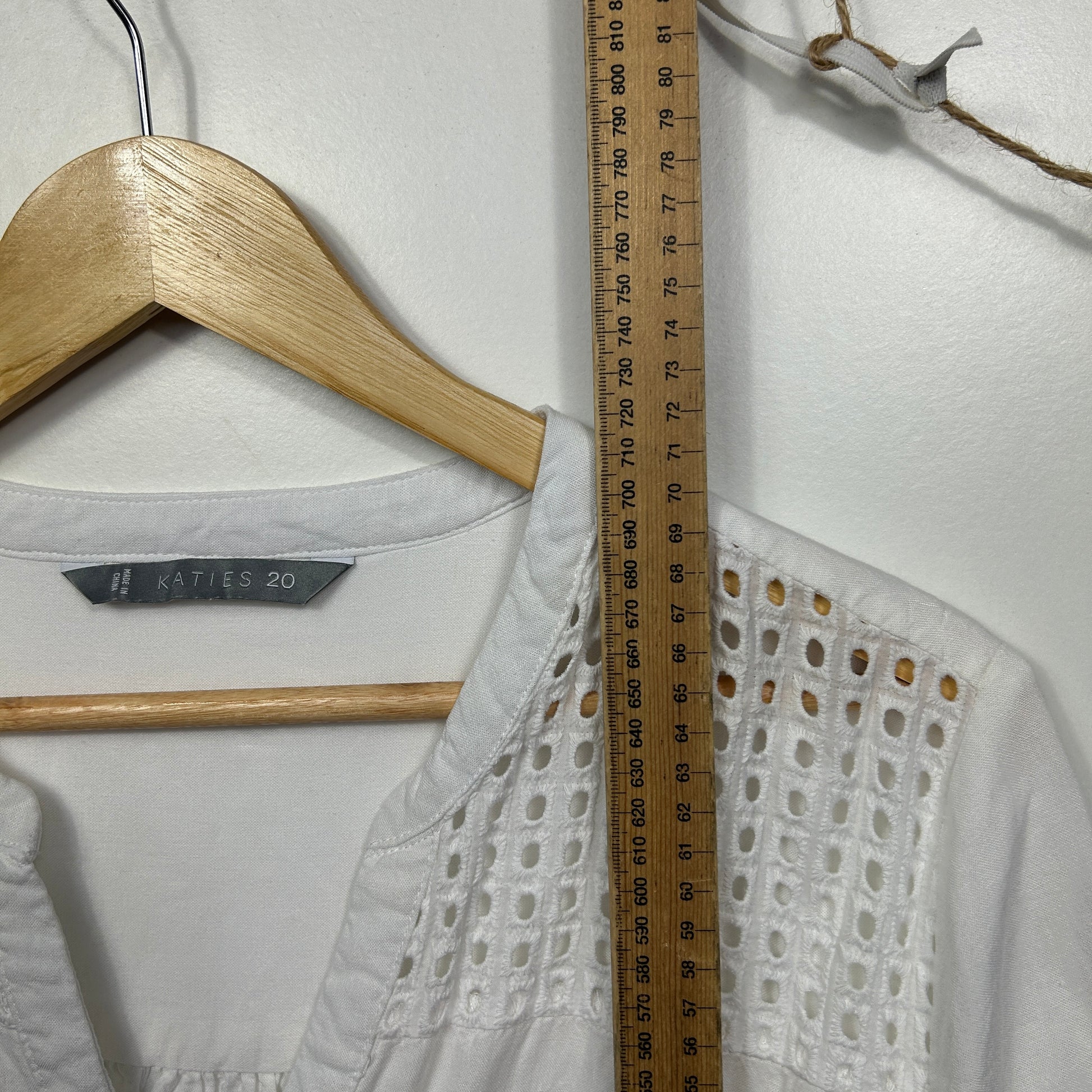 White shirt front view with eyelet detail measured against ruler