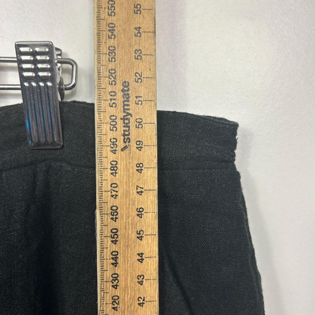 Black pants laid flat with measuring tape showing length