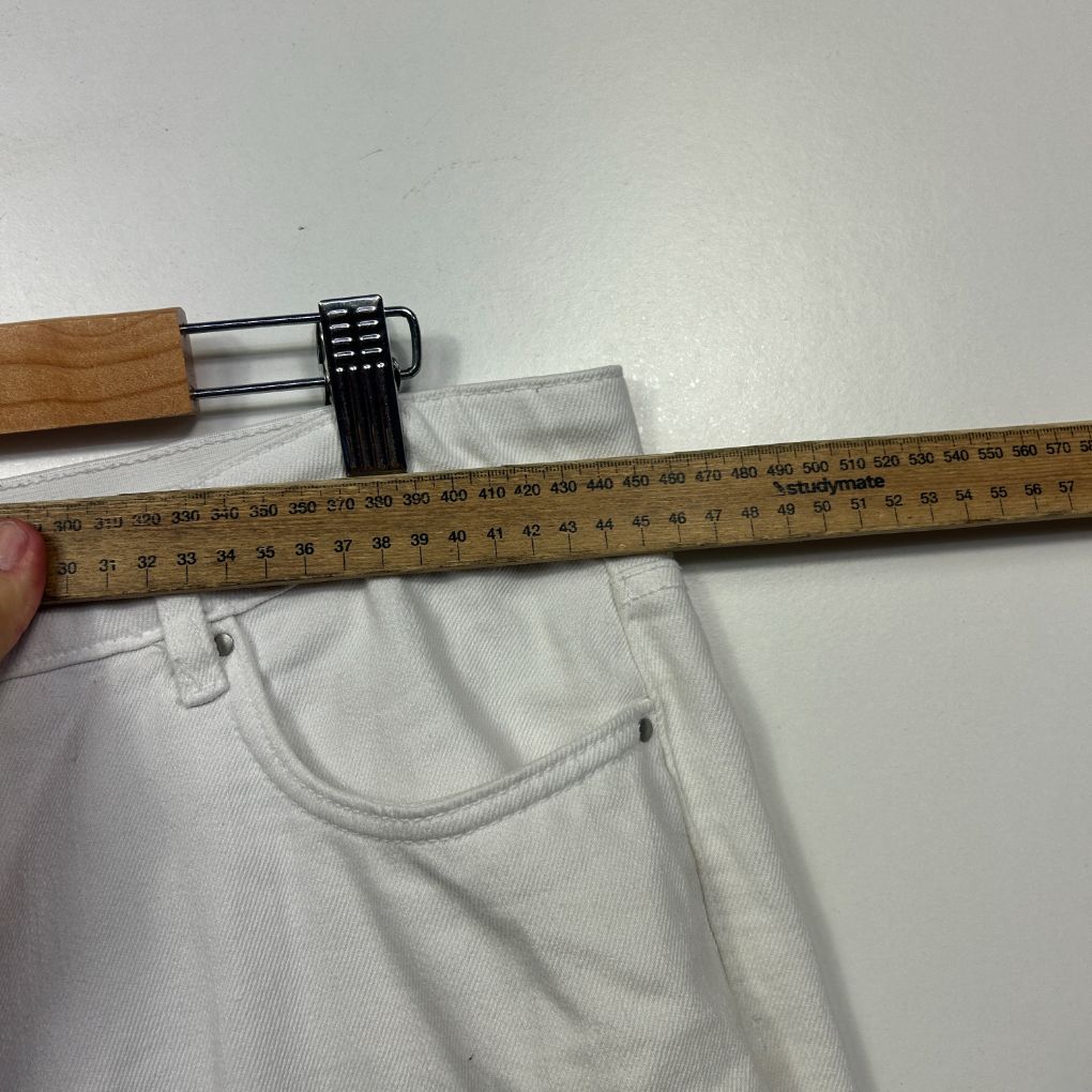 White pants waistband detail view with measuring tape