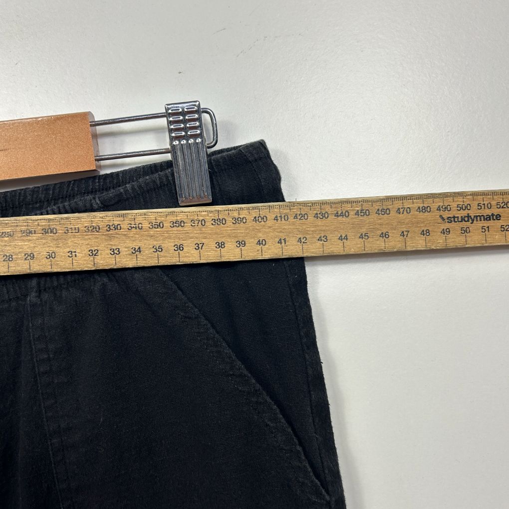 Black trousers waistband detail view with measuring tape