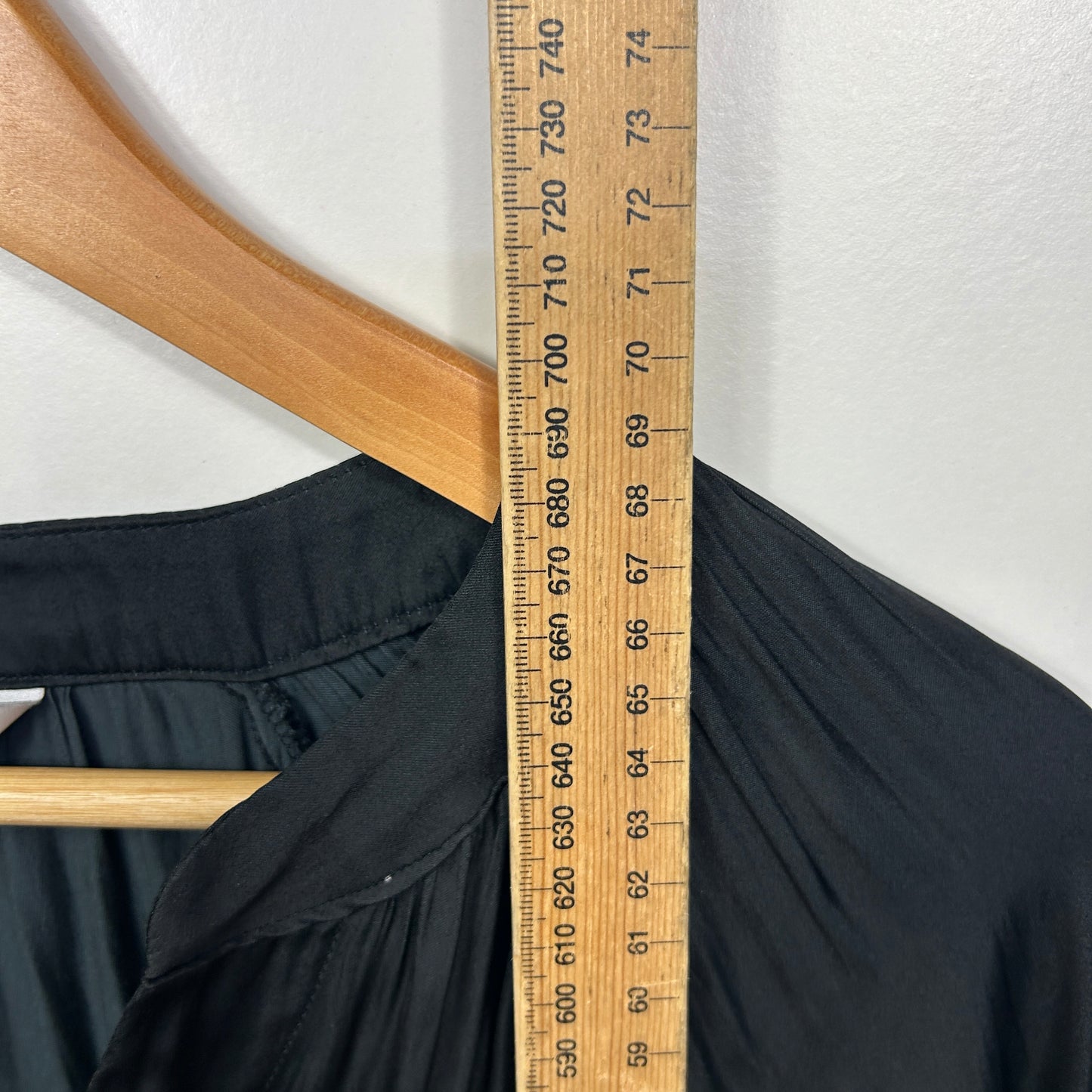 Black jacket front view on wooden hanger with measuring tape