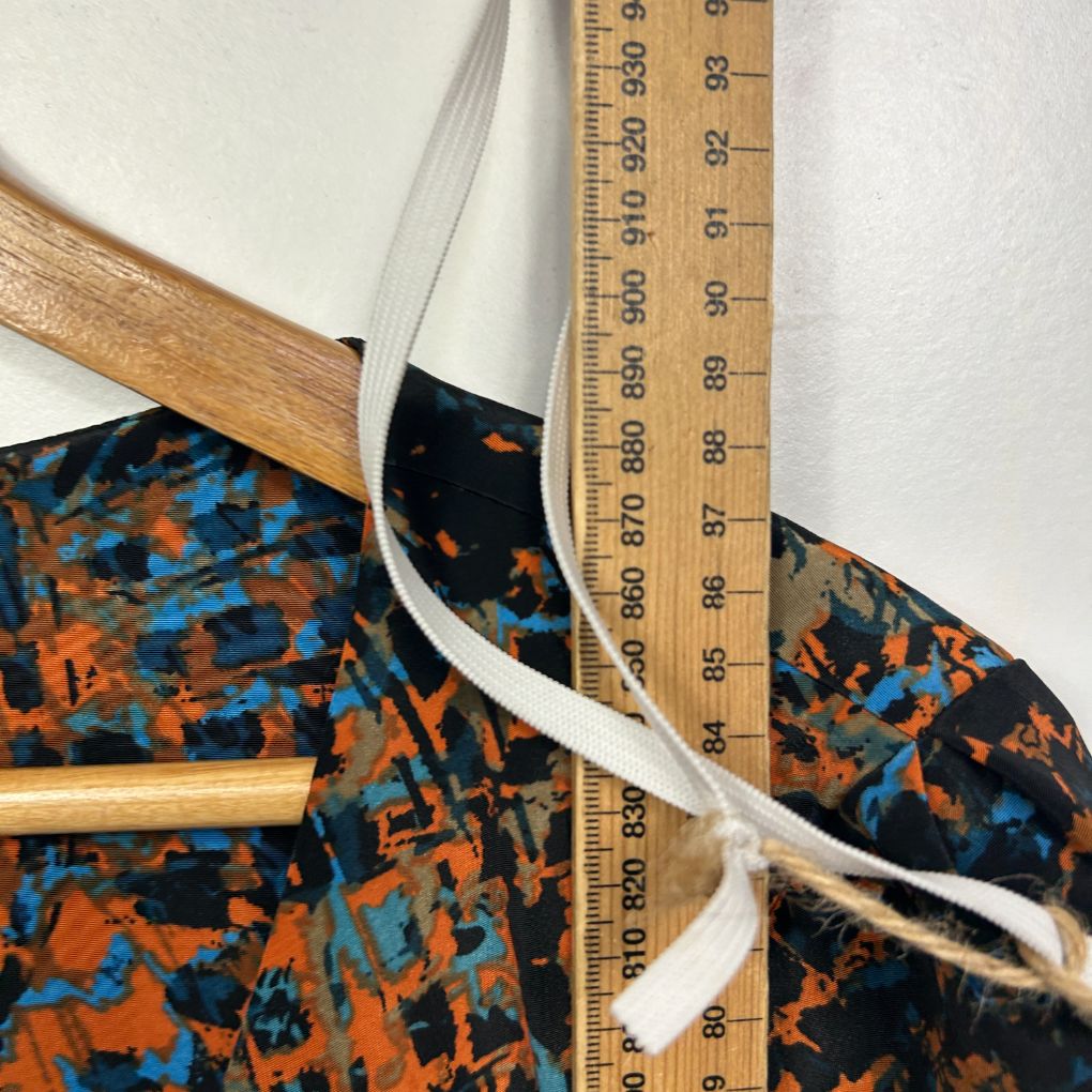 Orange and blue graphic patterned fabric detail view with wooden hanger and measuring tape