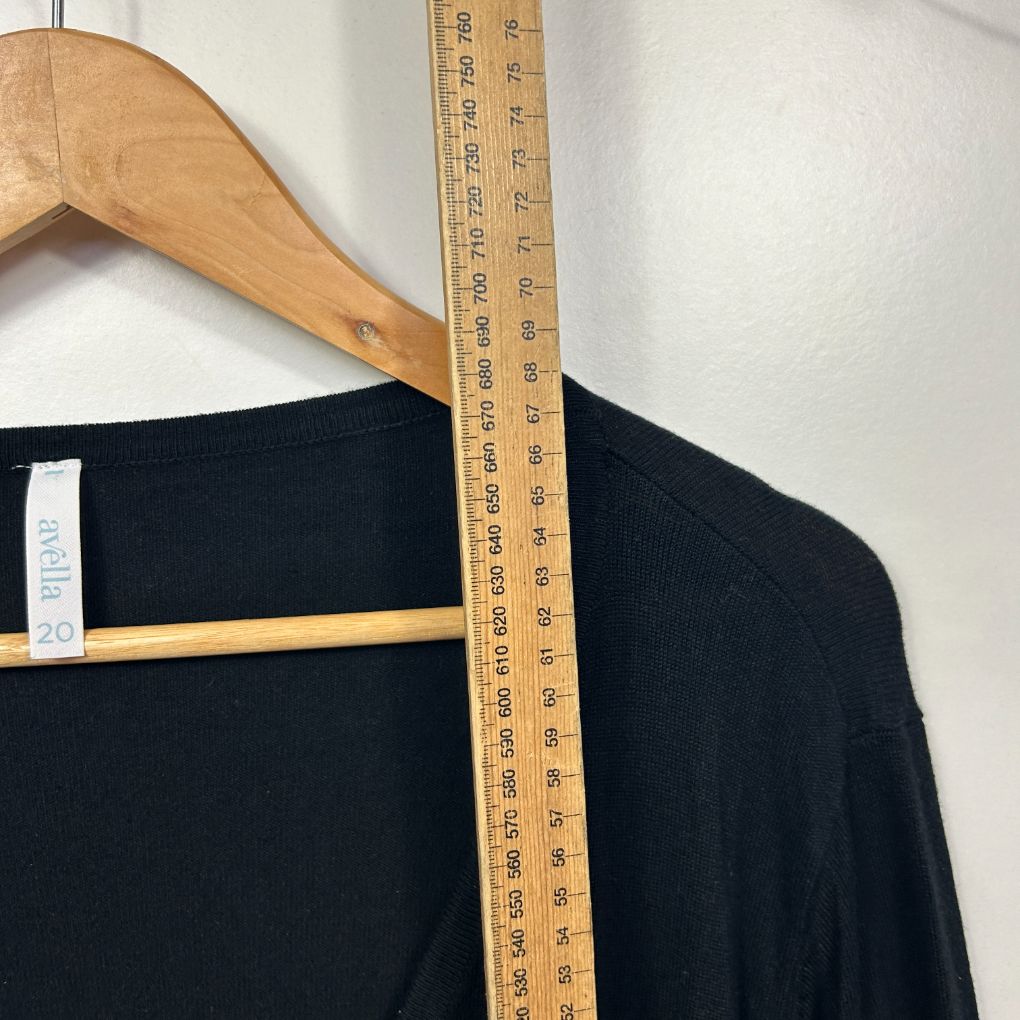 Black long sleeve top front view with wooden hanger and measuring ruler