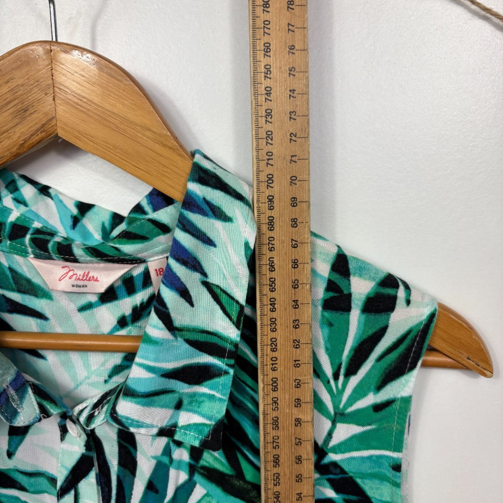 Green and white tropical leaf print shirt front view on wooden hanger with measuring tape