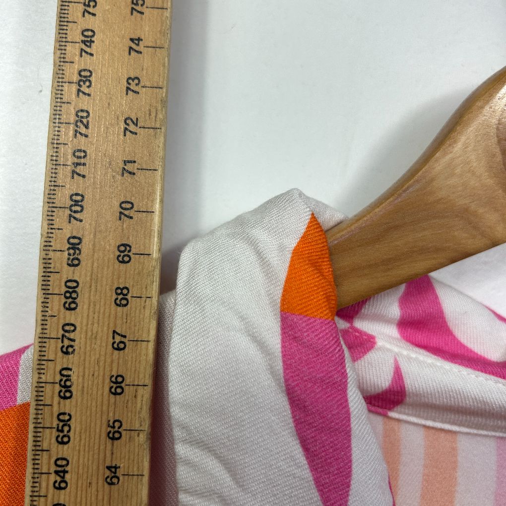 Orange and pink patterned fabric detail view with measuring tape