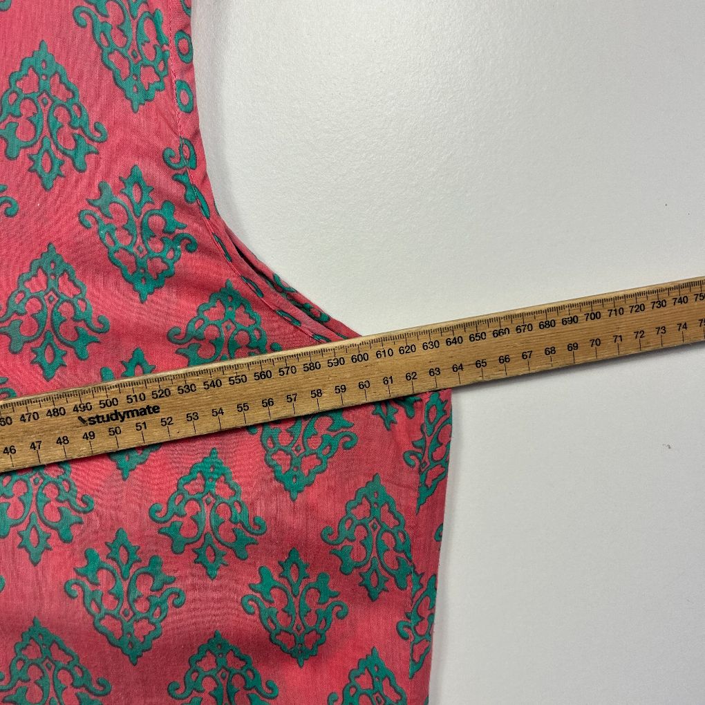 Pink damask patterned garment detail view with measurement tape