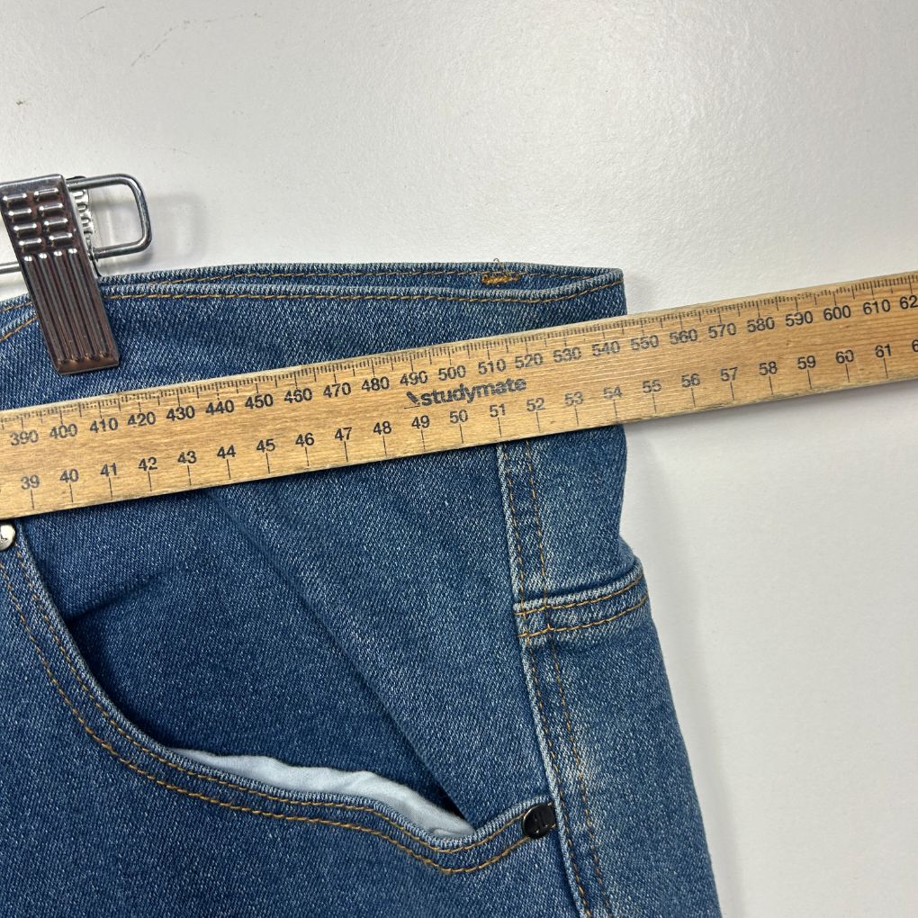 Blue denim jeans waistband detail view with measuring tape