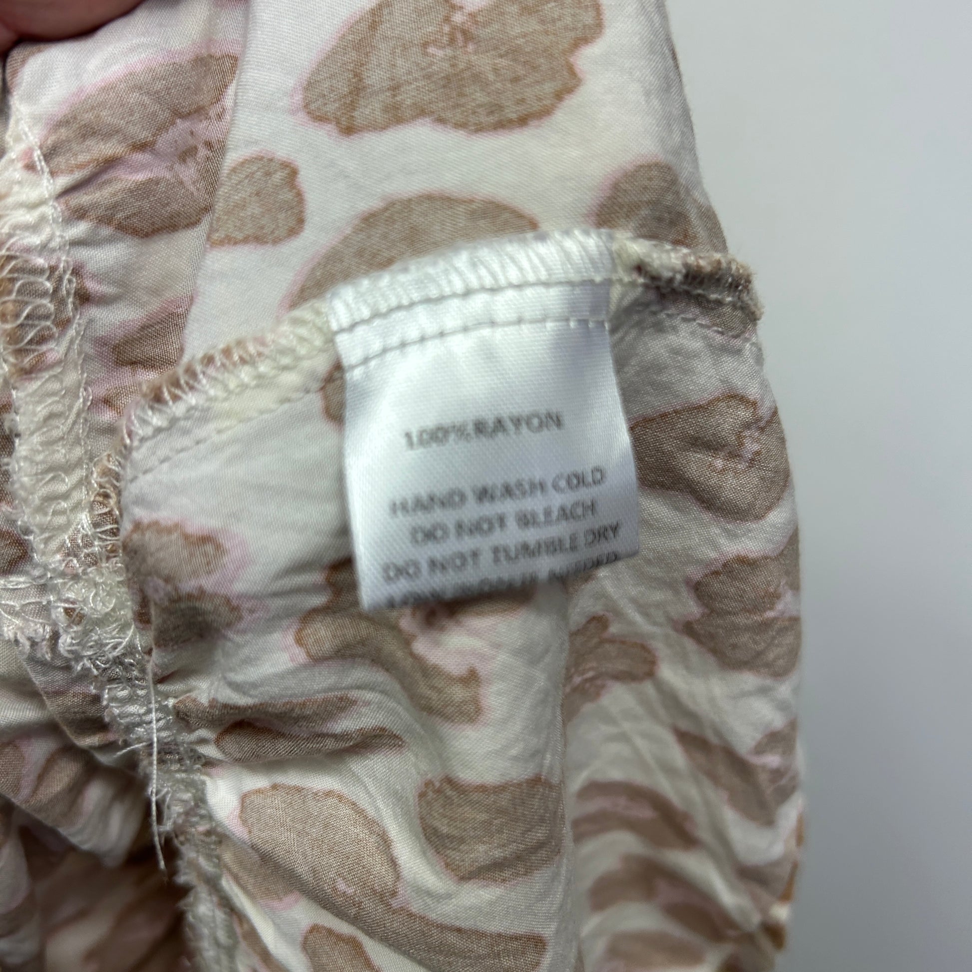 Beige and cream patterned garment detail view showing care label