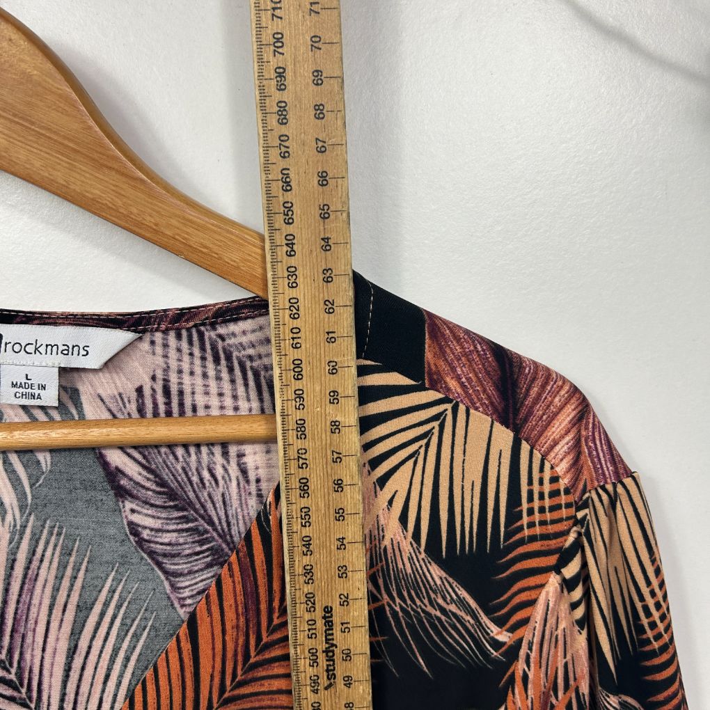 Tropical palm print shirt detail view with wooden hanger and measuring tape