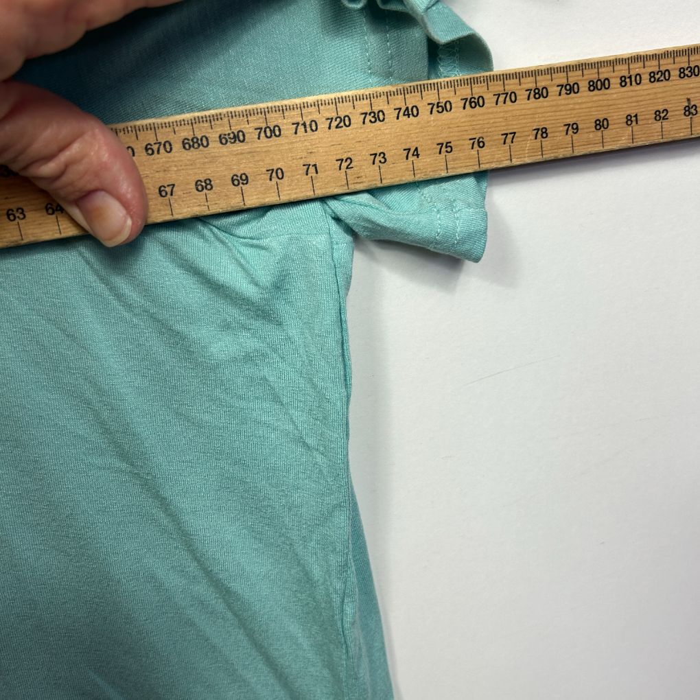 Teal t-shirt being measured with tape measure detail view