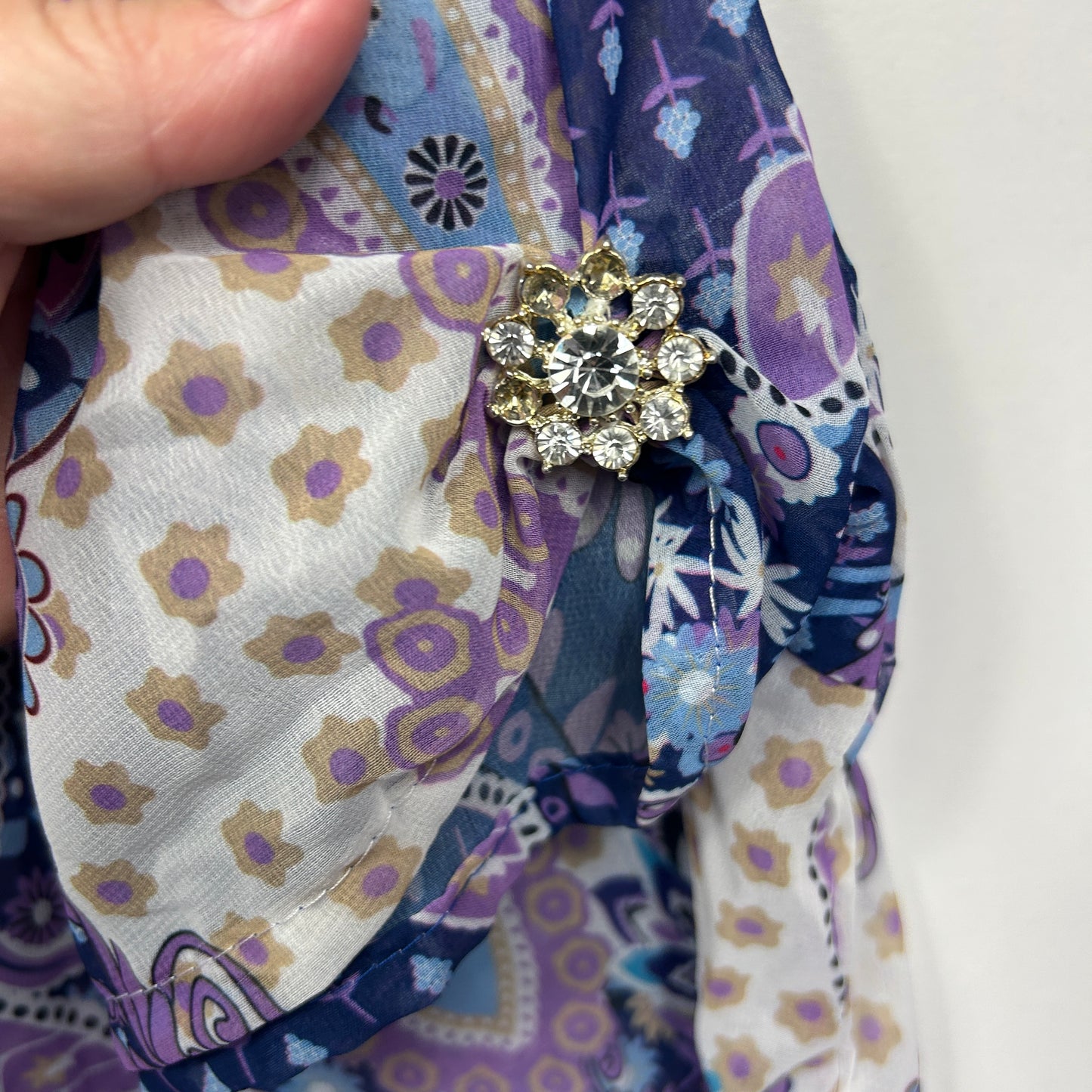 Purple floral scarf detail view with gold brooch