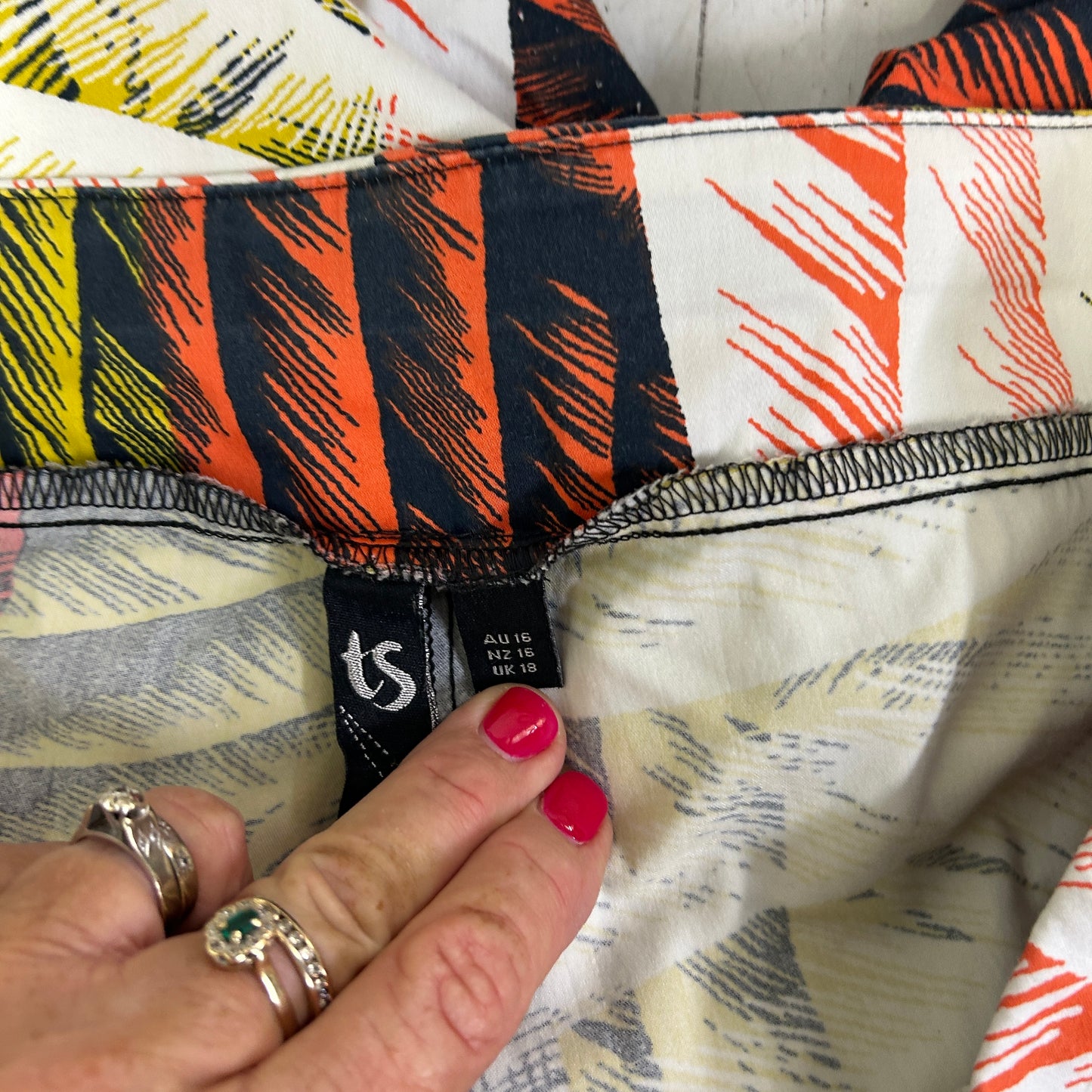 Colorful striped fabric detail view with hand holding label