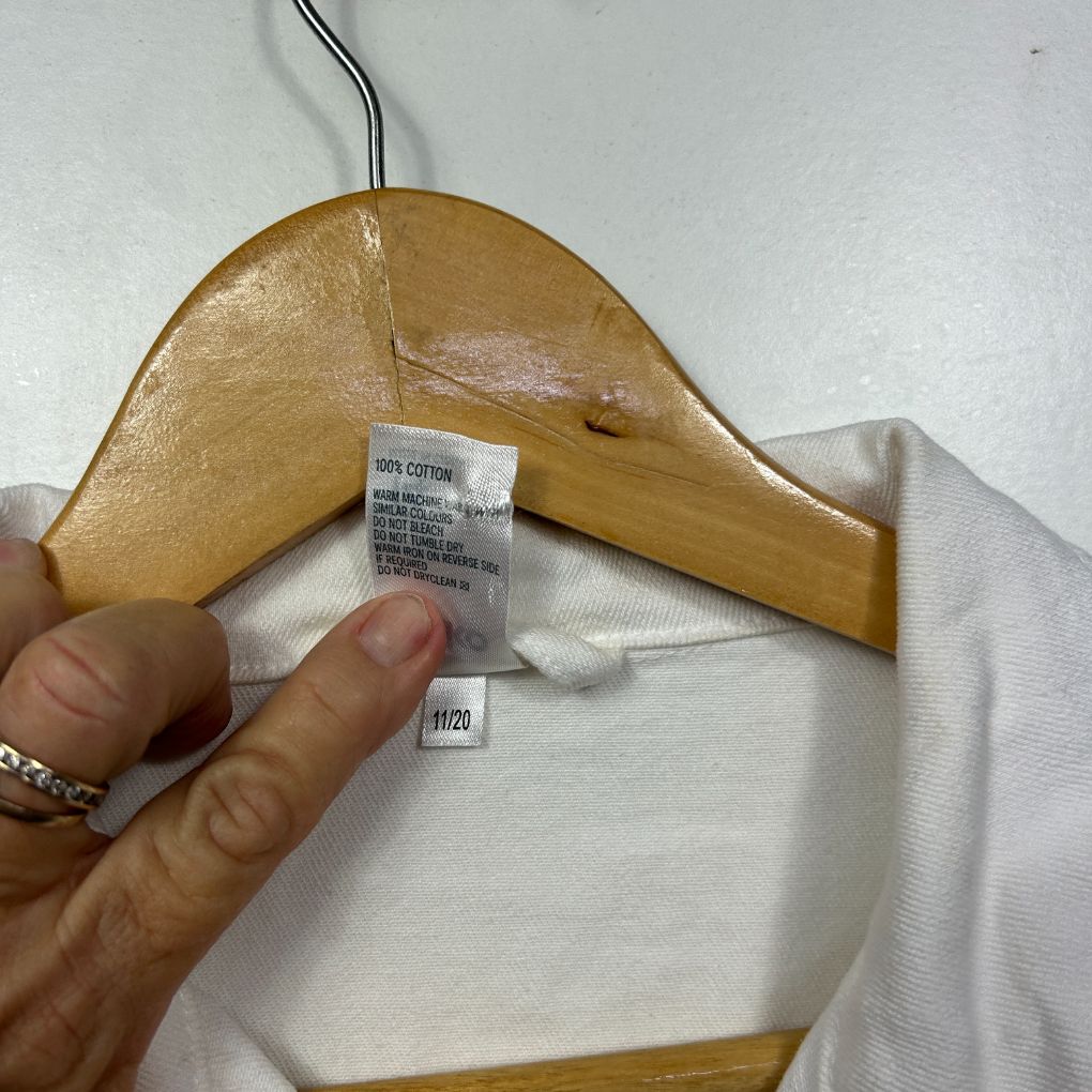 White shirt label and wooden hanger detail view