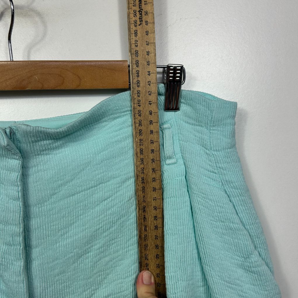 Mint green ribbed pants detail view with measuring tape