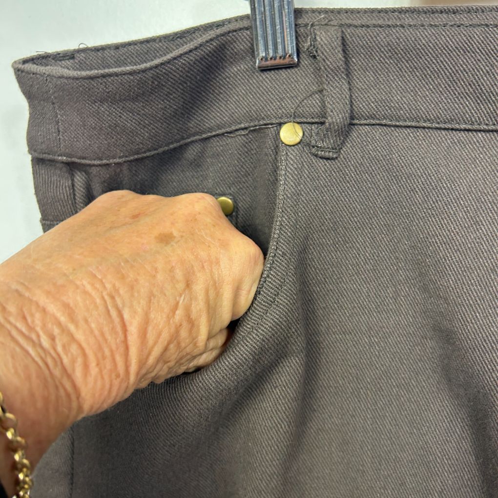 Grey trousers front detail view showing button and pocket
