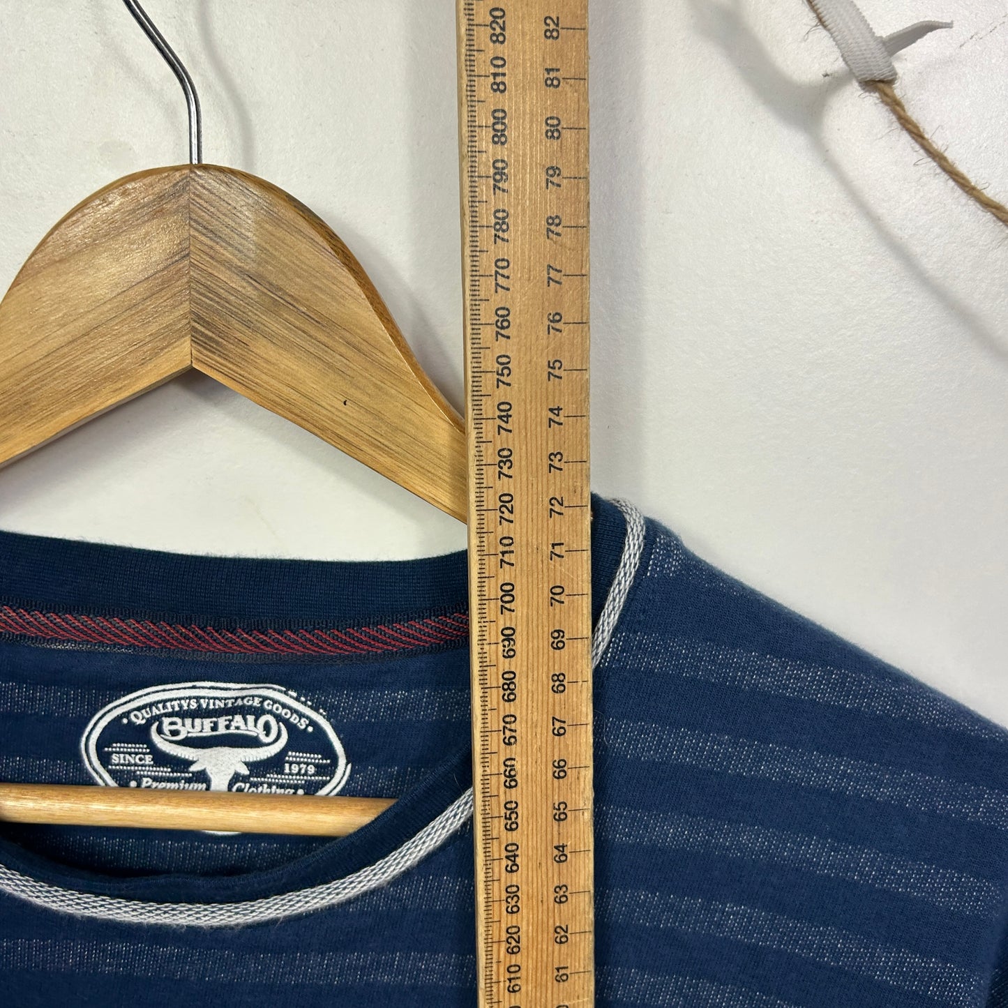 Navy striped long sleeve top front view on wooden hanger with measuring tape