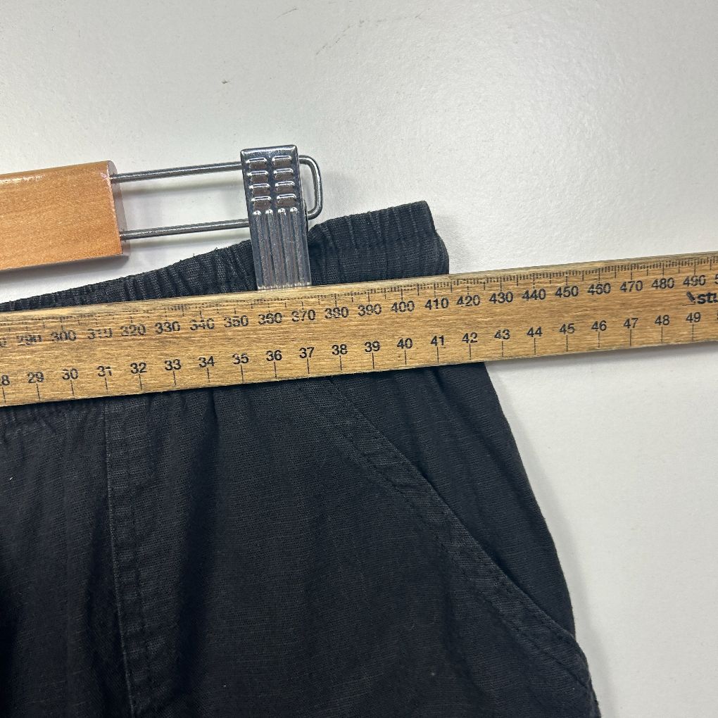 Black pants with measuring tape and wooden hanger detail view