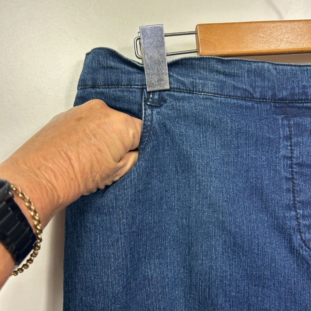Blue denim jeans detail view with wooden hanger